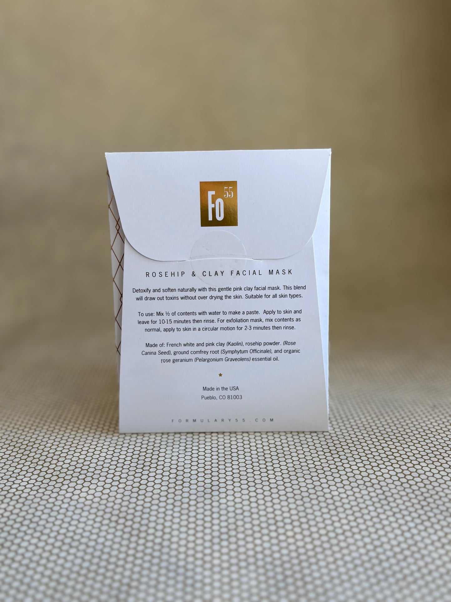 back of Formulary 55 rosehip and clay facial mask packaging on a textured surface with a neutral background