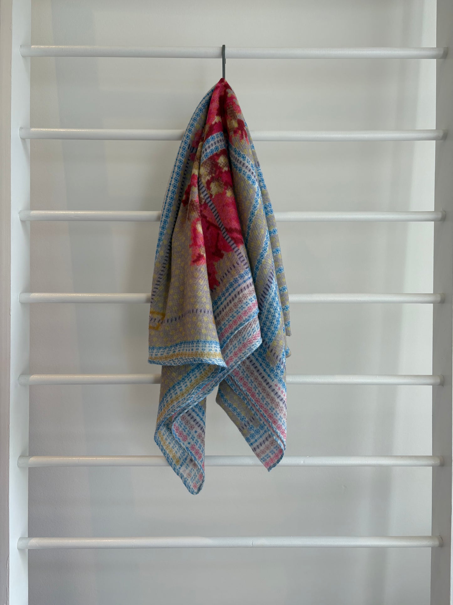 floral brightly colored scarf on rack pink, blue, red, yellow brown design.