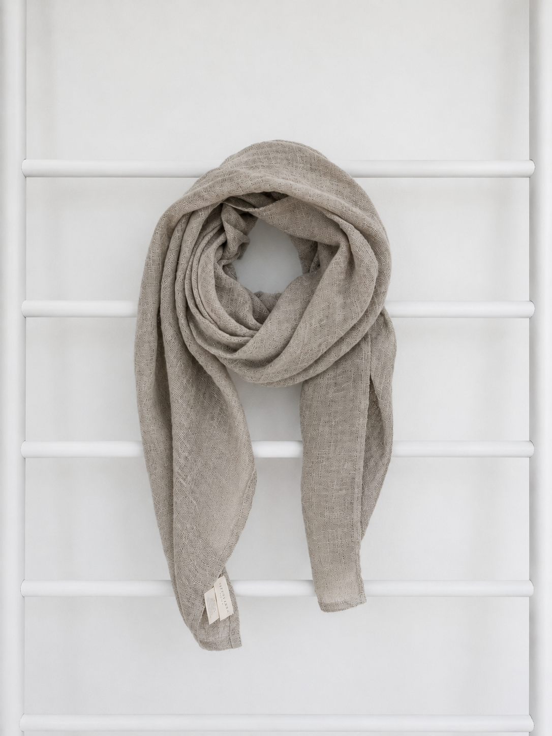 Beige linen scarf draped over a white lattice background