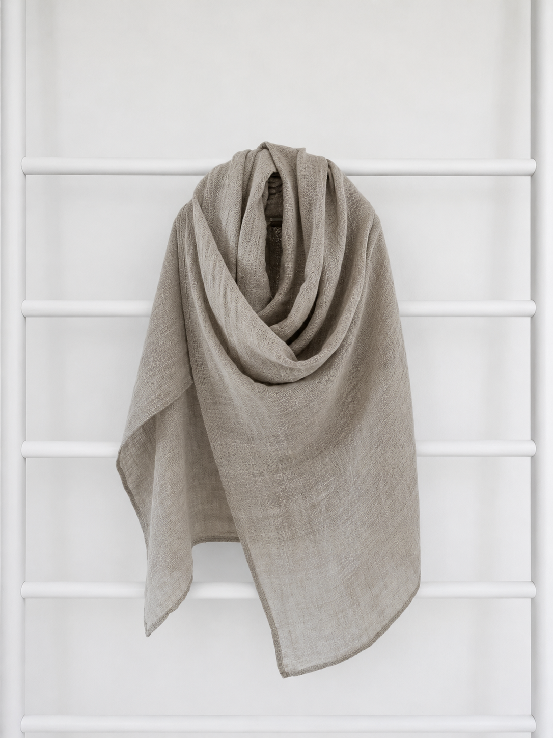 Beige linen scarf draped over a white lattice background