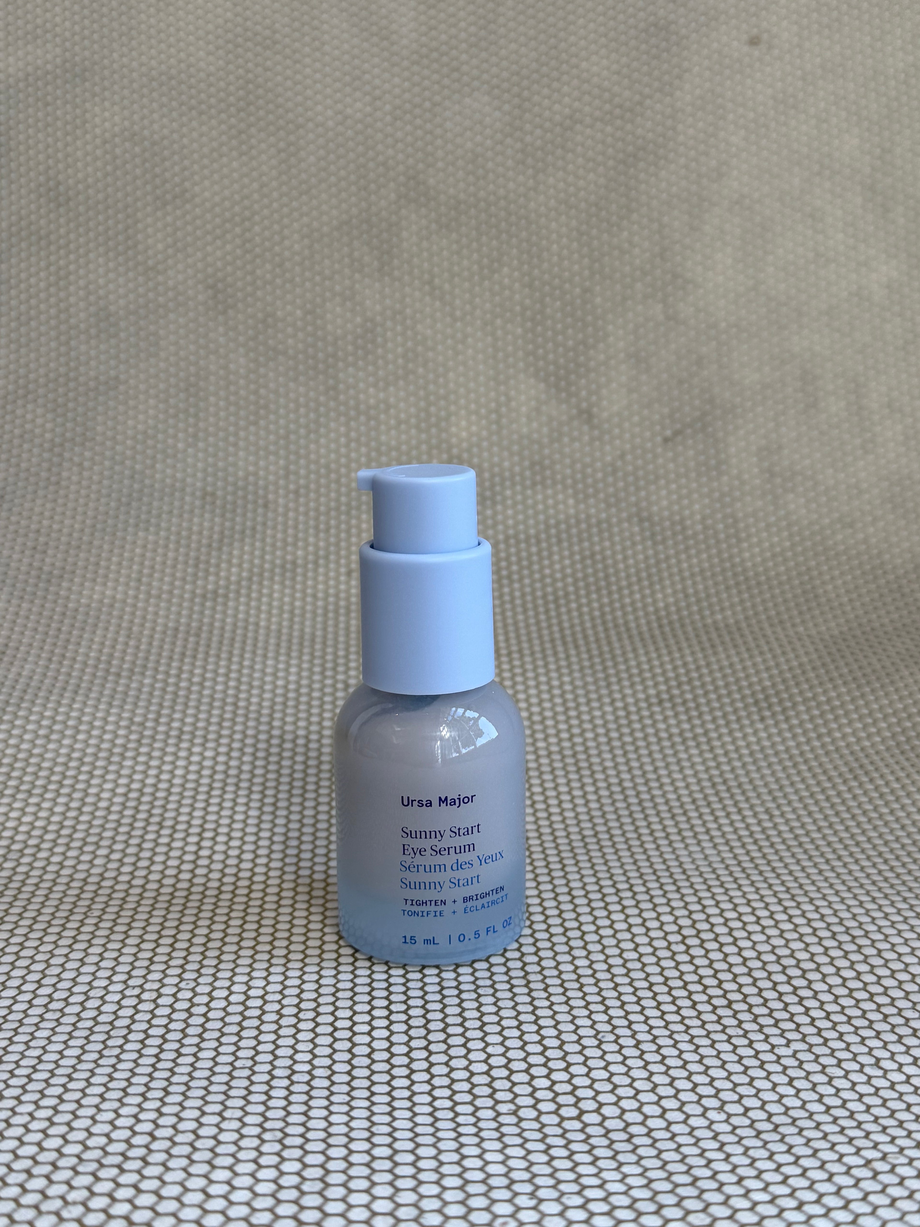 small light blue pump bottle of Ursa Major Sunny Start Eye Serum on neutral background. 