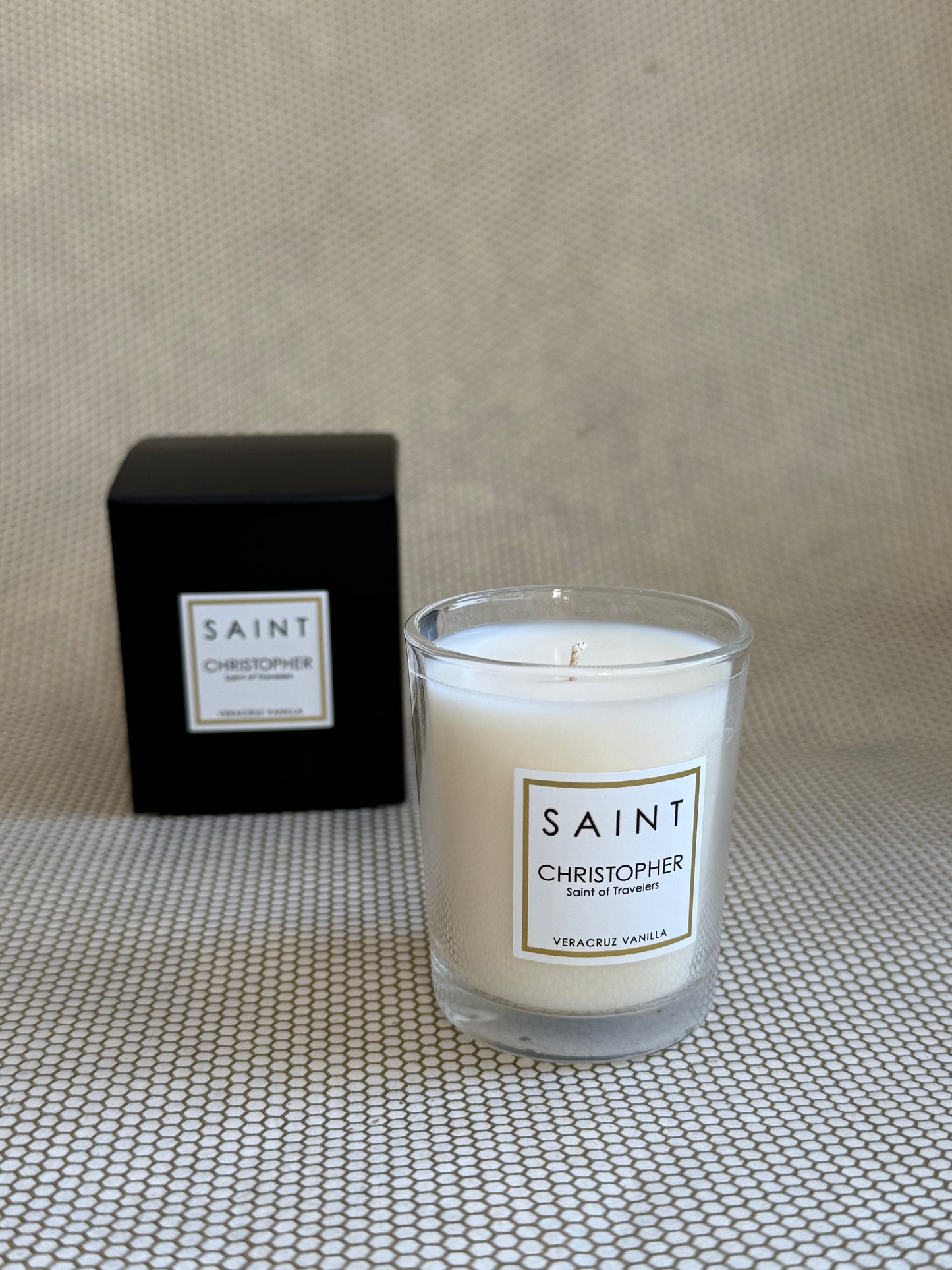 SAINT small votive candle. clear glass white wax in black box. saint christopher vanilla. 3 oz.(2.5 oz. pour). Measures 2.5"Hx2"D.