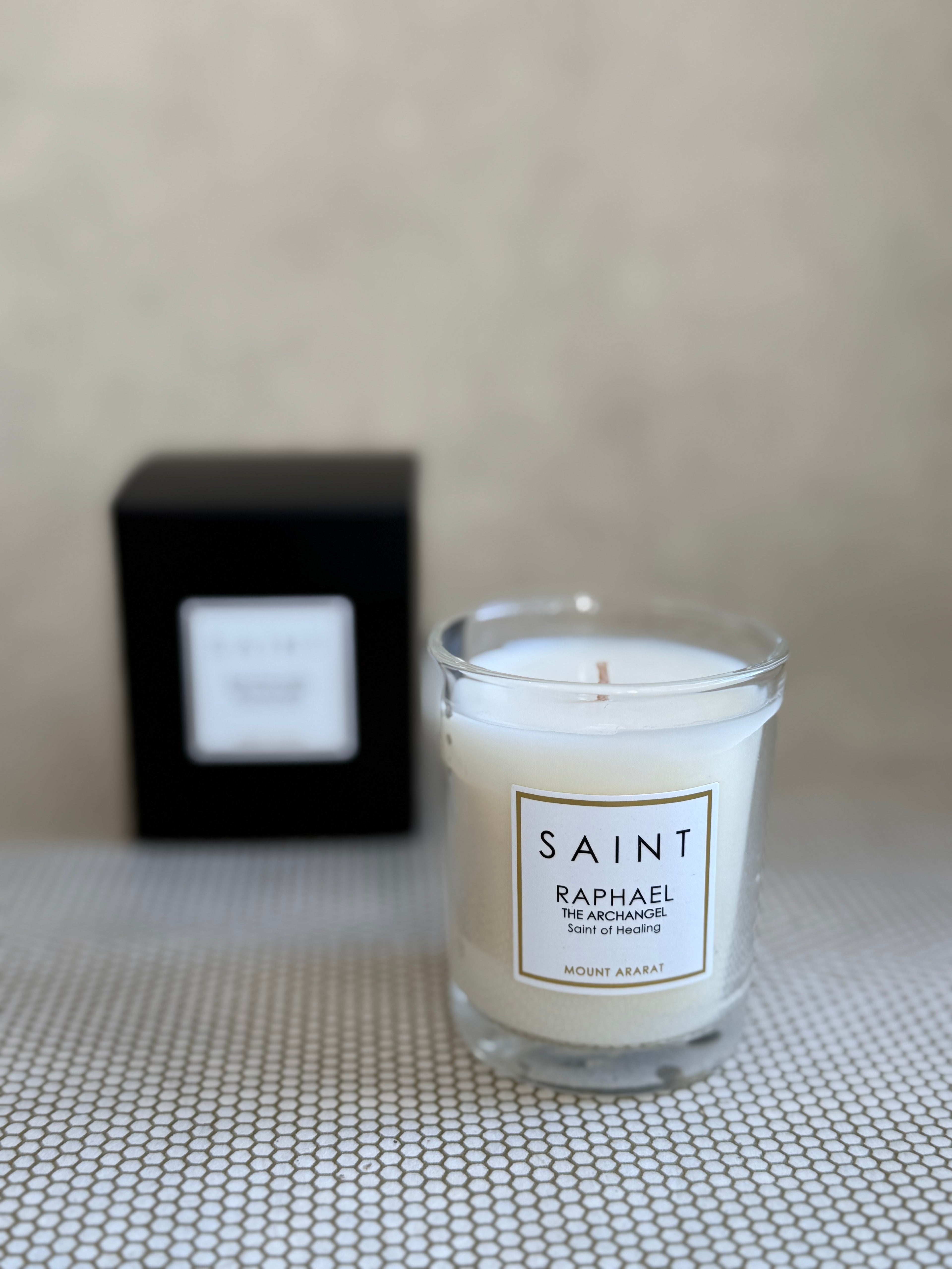 SAINT small votive candle. clear glass white wax in black box. raphael mount ararat. 3 oz.(2.5 oz. pour). Measures 2.5"Hx2"D.