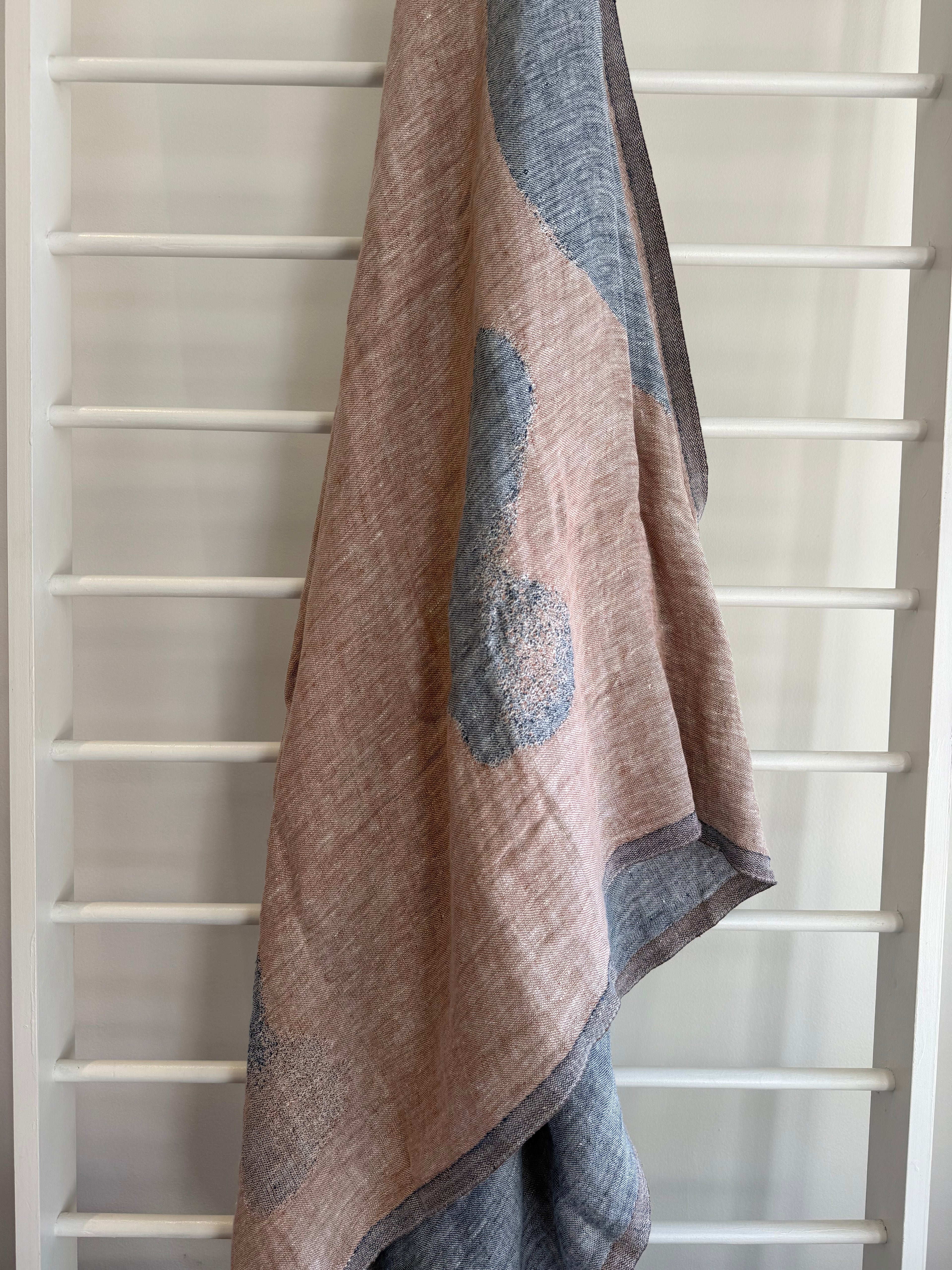 Textured towel with a geometric pattern draped over a white ladder. foggy blue and cinnamon towel linen.