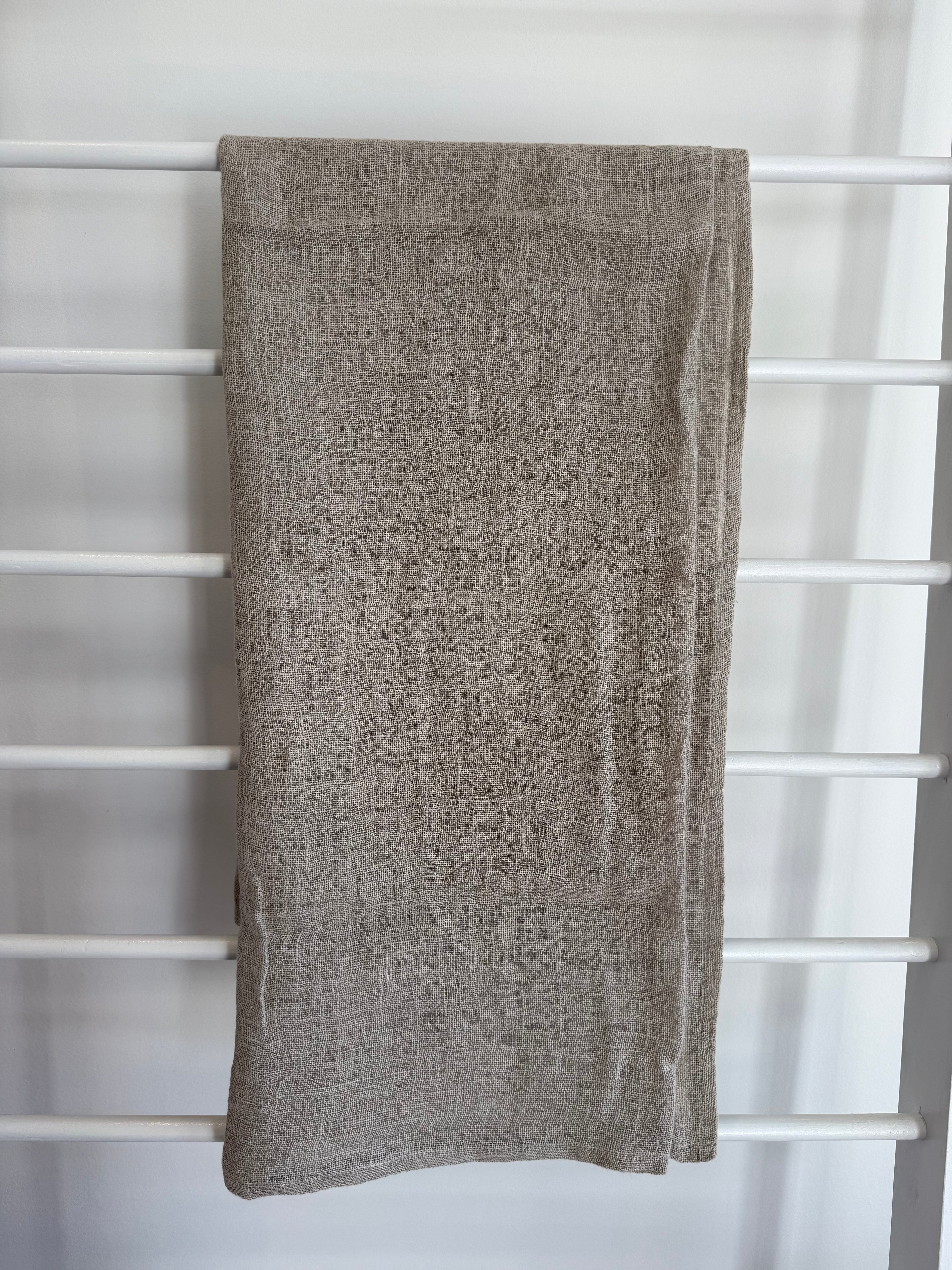 Beige linen scarf draped over a white lattice background