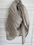 Beige linen scarf draped over a white lattice background