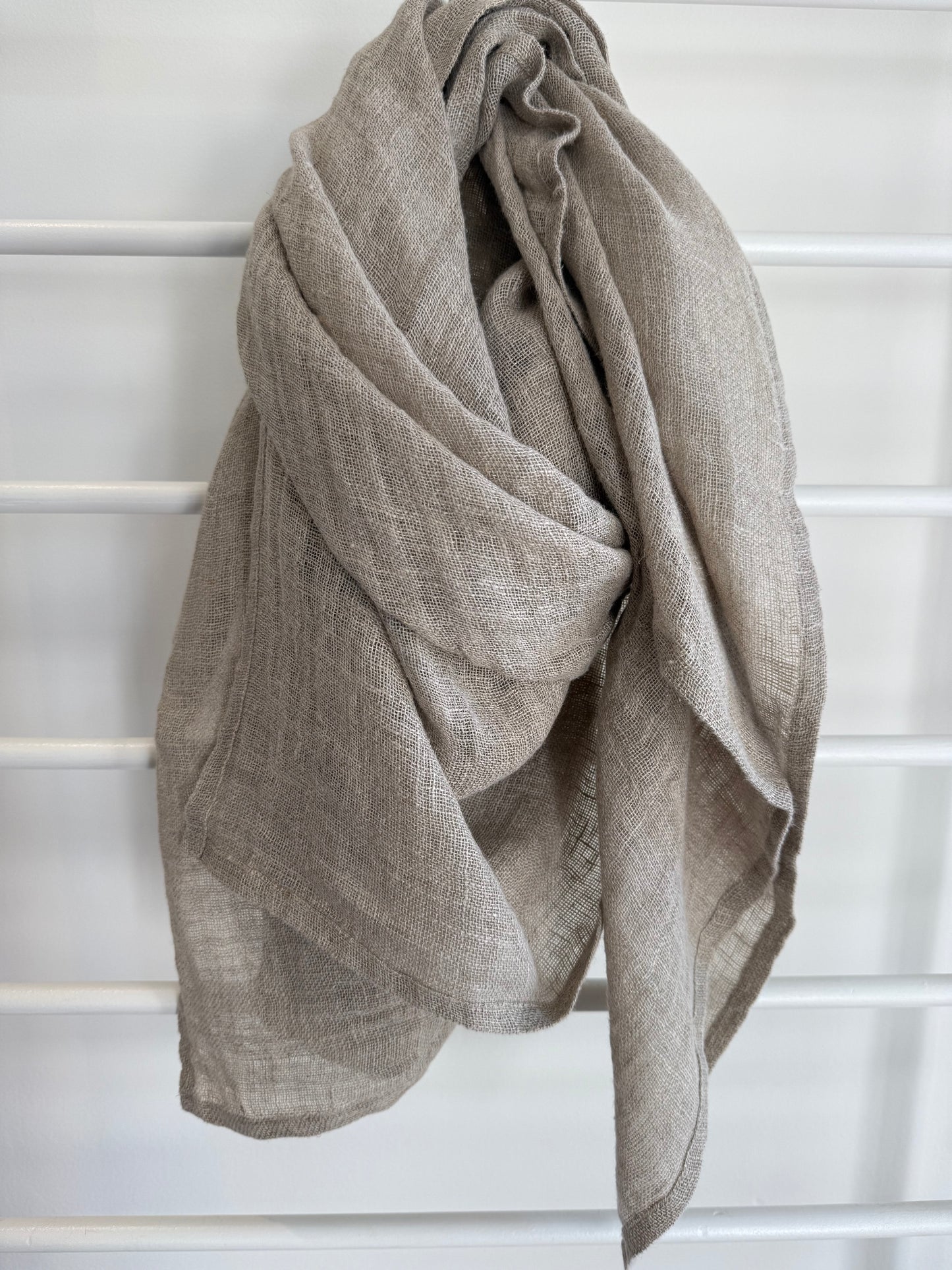 Beige linen scarf draped over a white lattice background