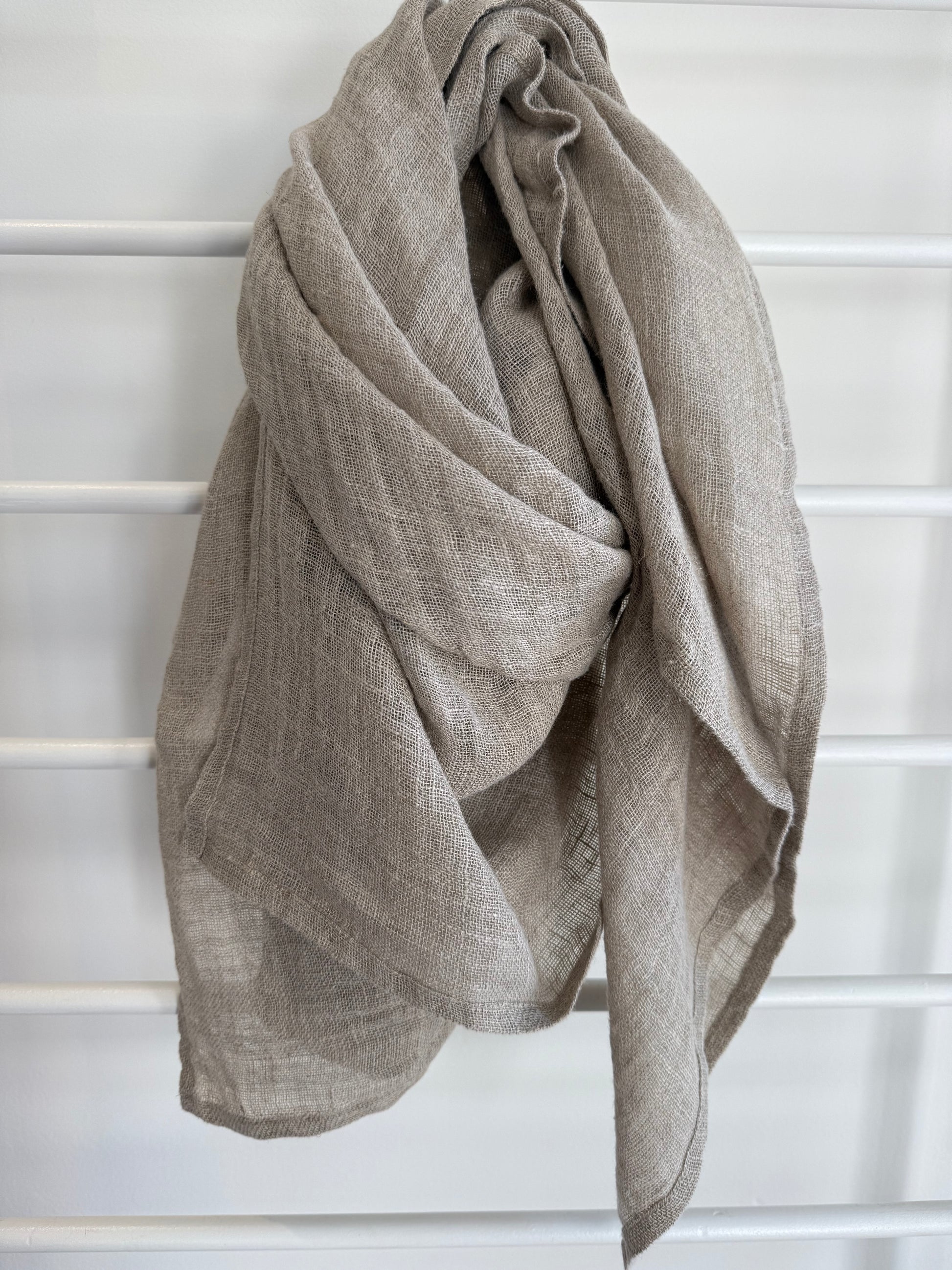 Beige linen scarf draped over a white lattice background