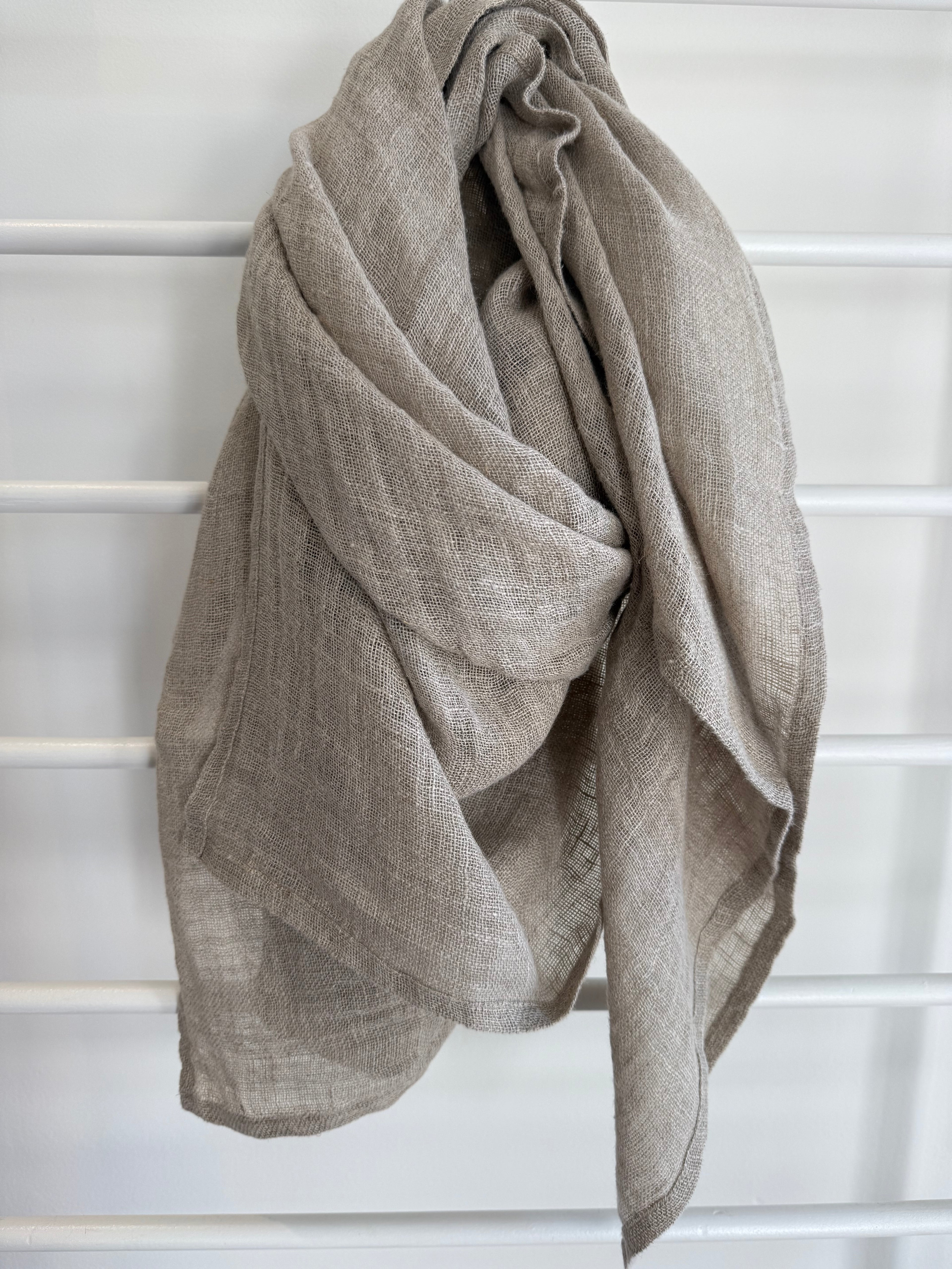 Beige linen scarf draped over a white lattice background
