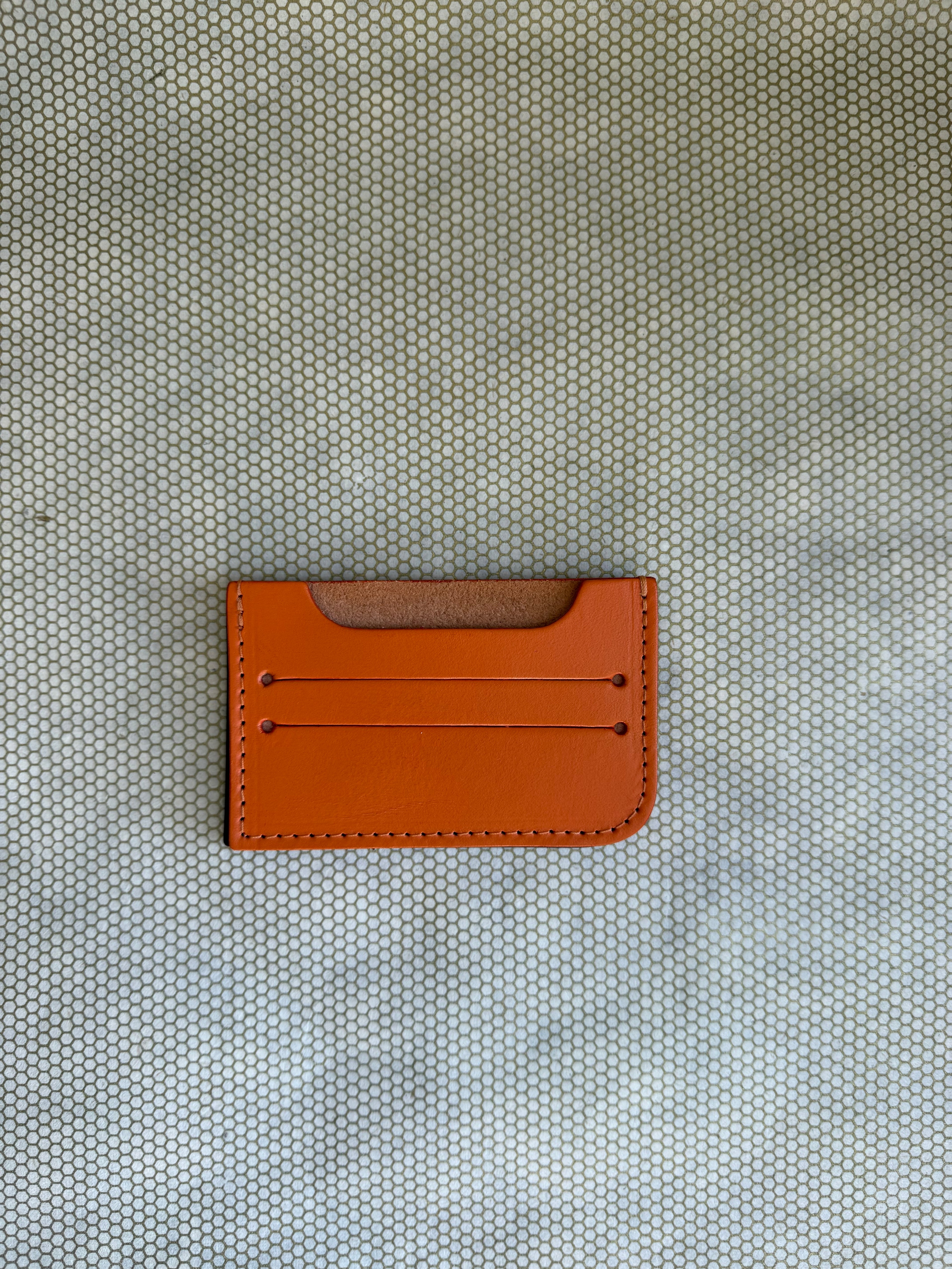 Orange leather cardholder on a textured gray background