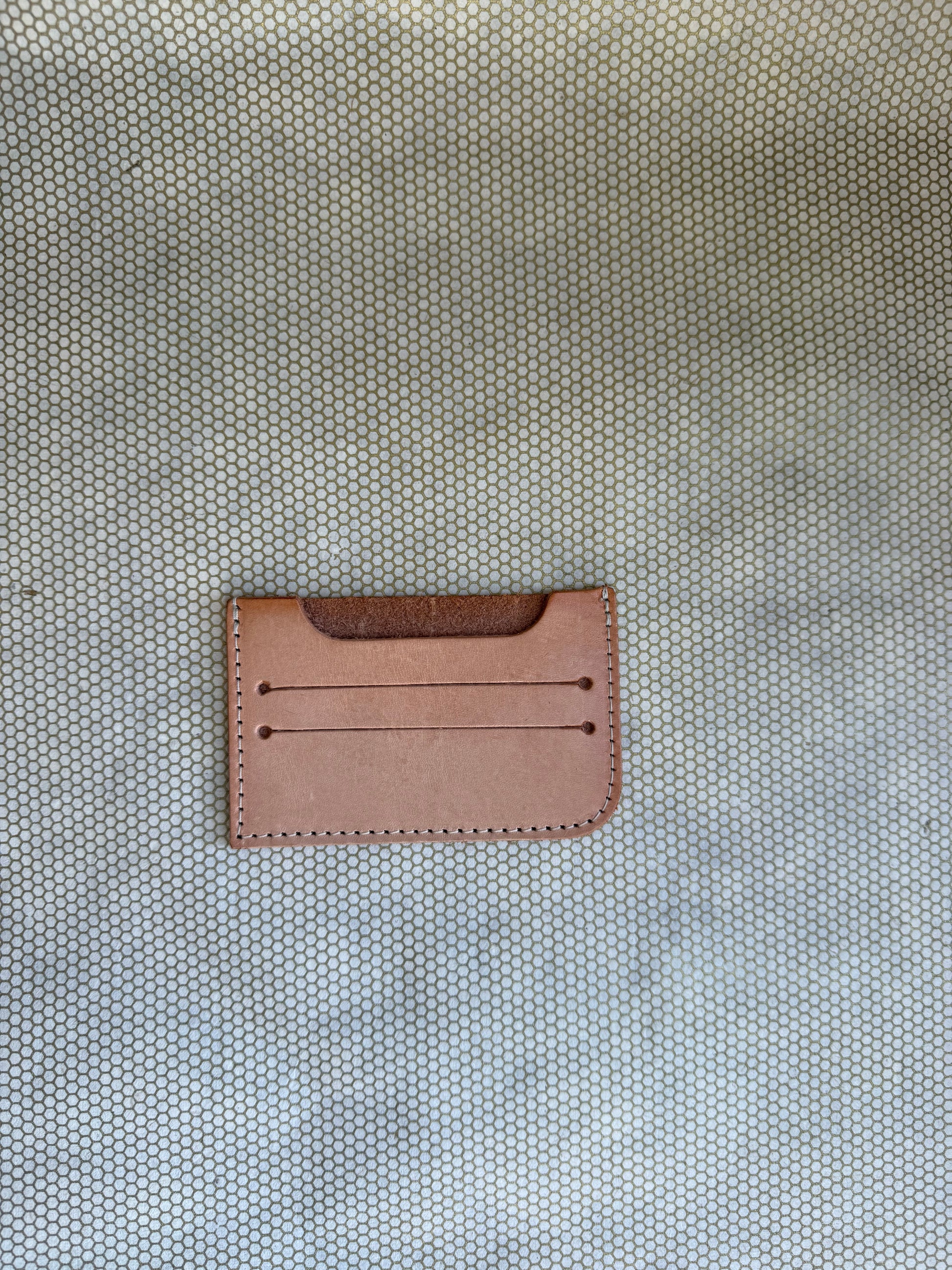 Brown leather cardholder on a textured beige background