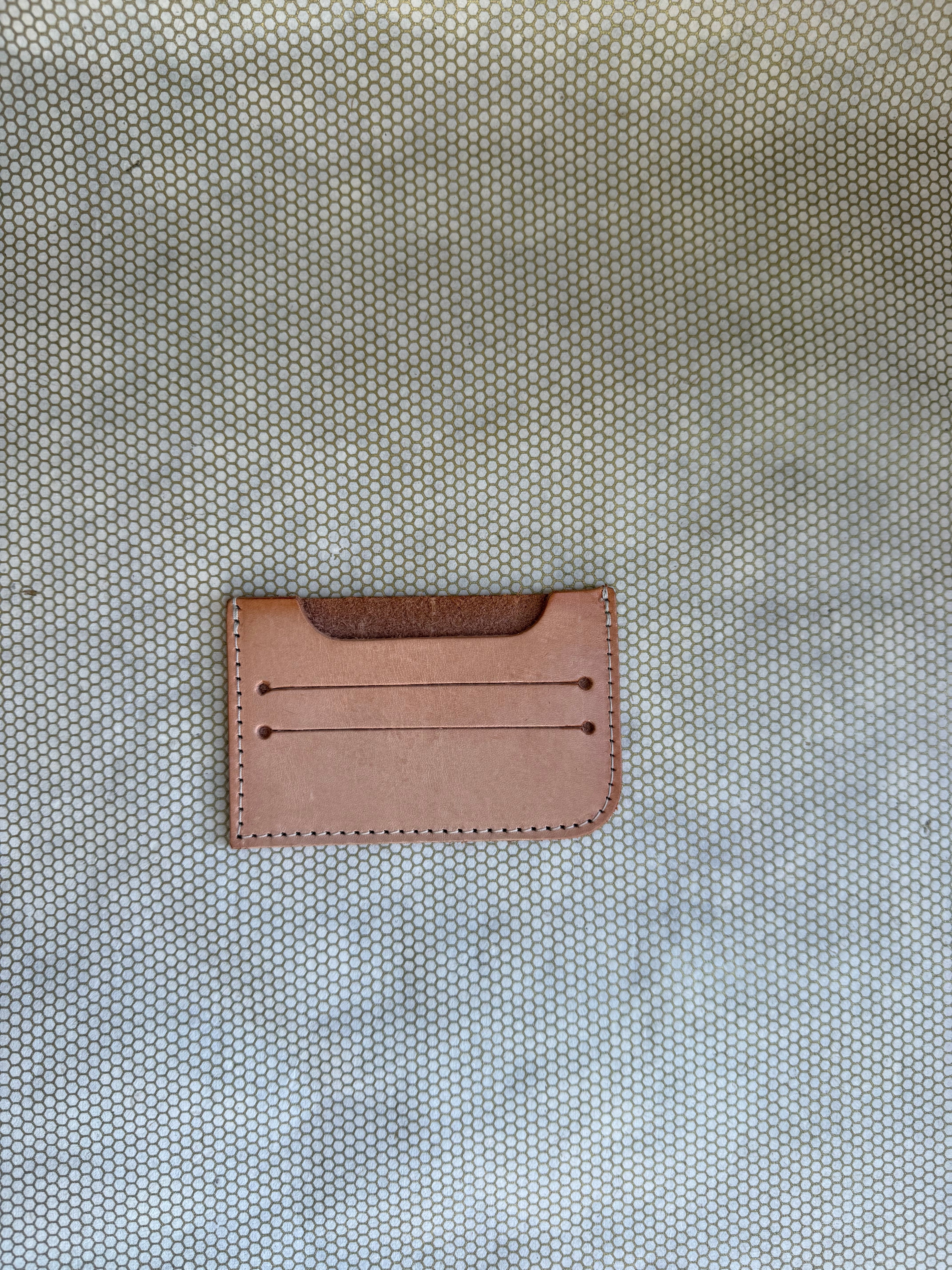 Brown leather cardholder on a textured beige background