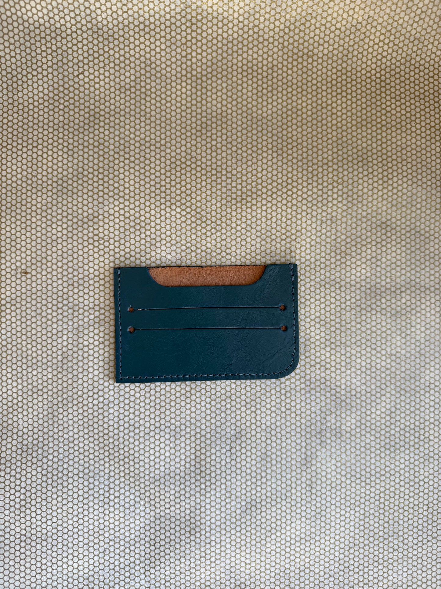 Blue leather cardholder on a textured beige surface