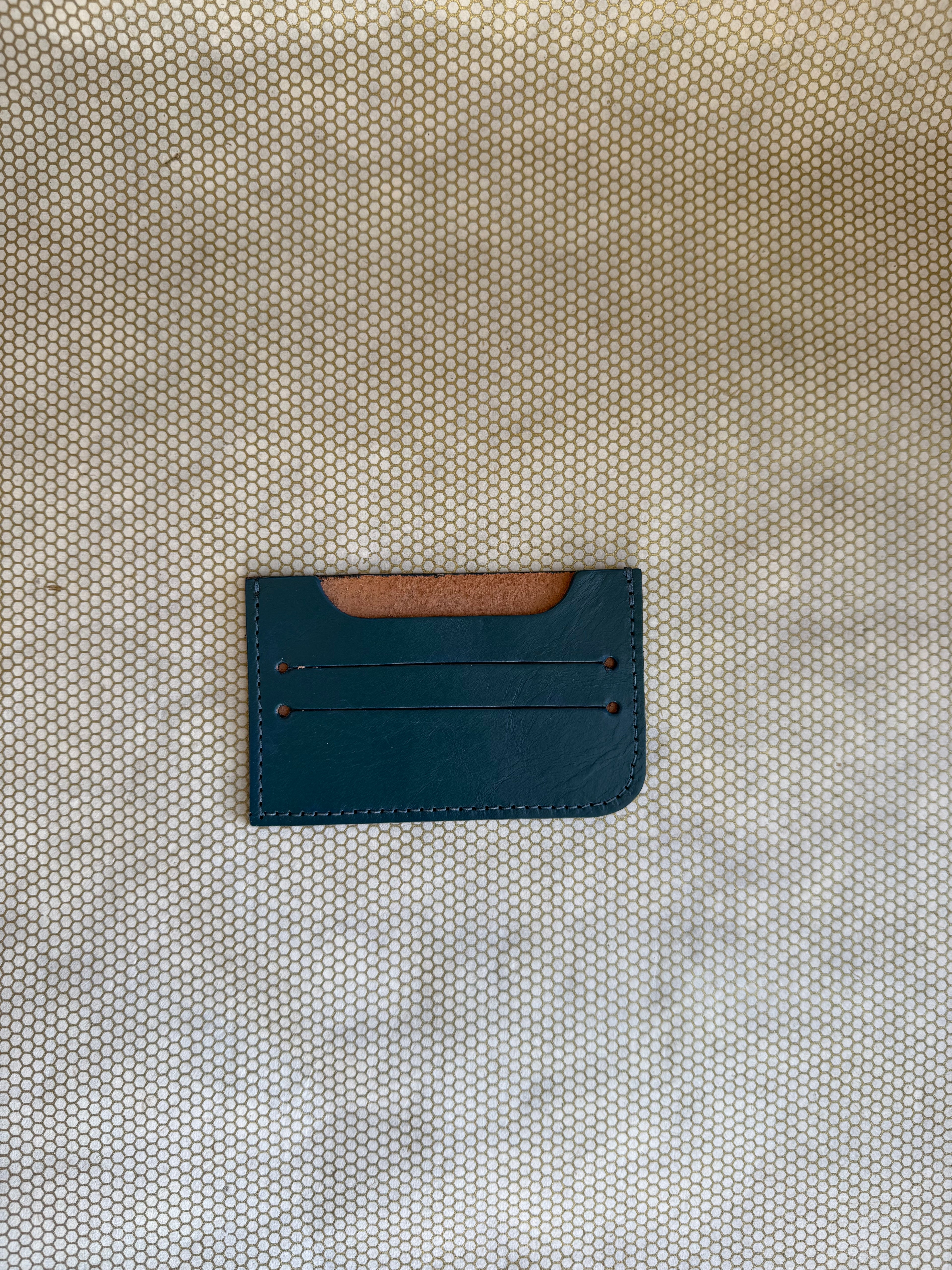 Blue leather cardholder on a textured beige surface