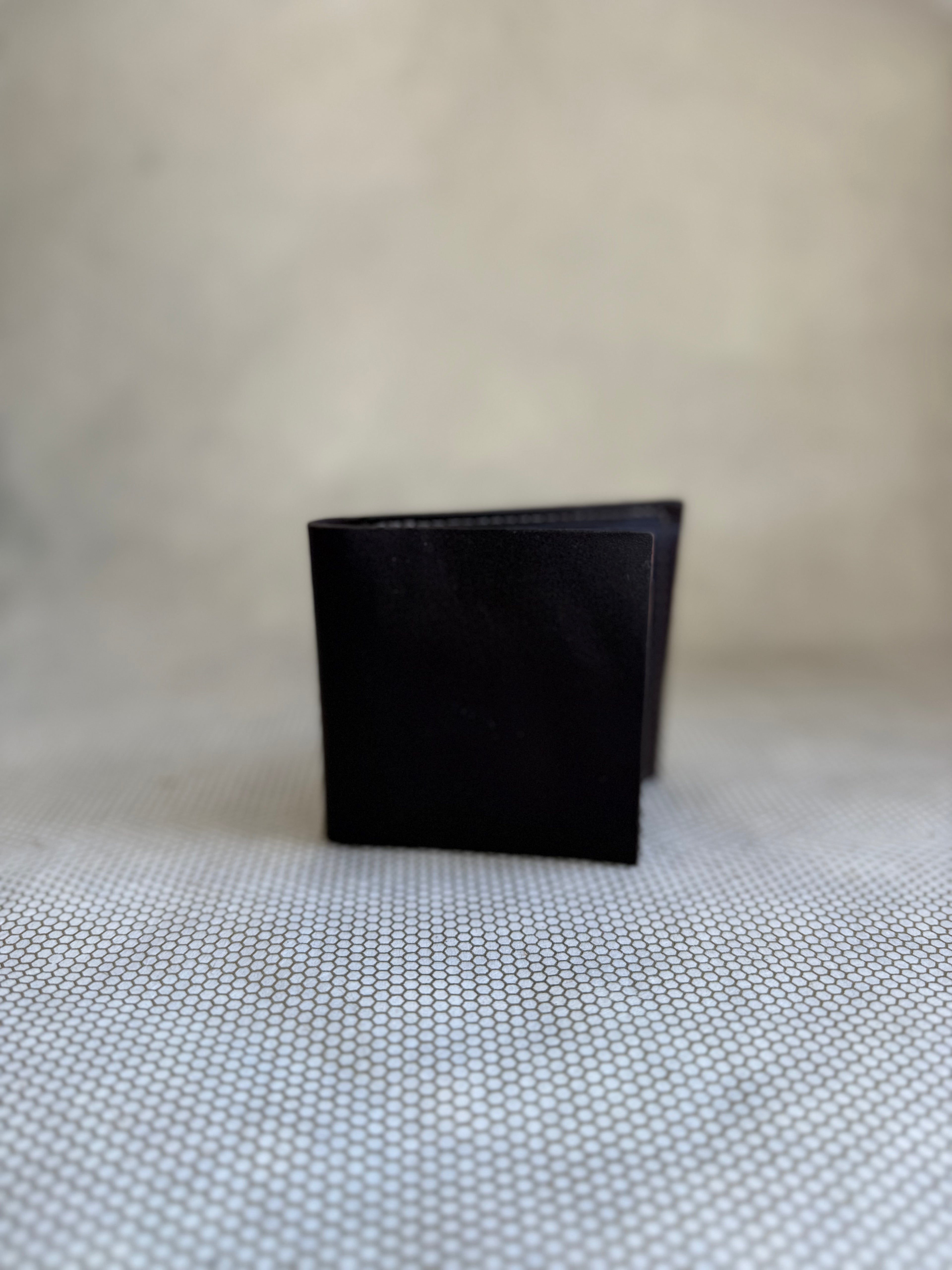 Black leather wallet on a textured beige surface