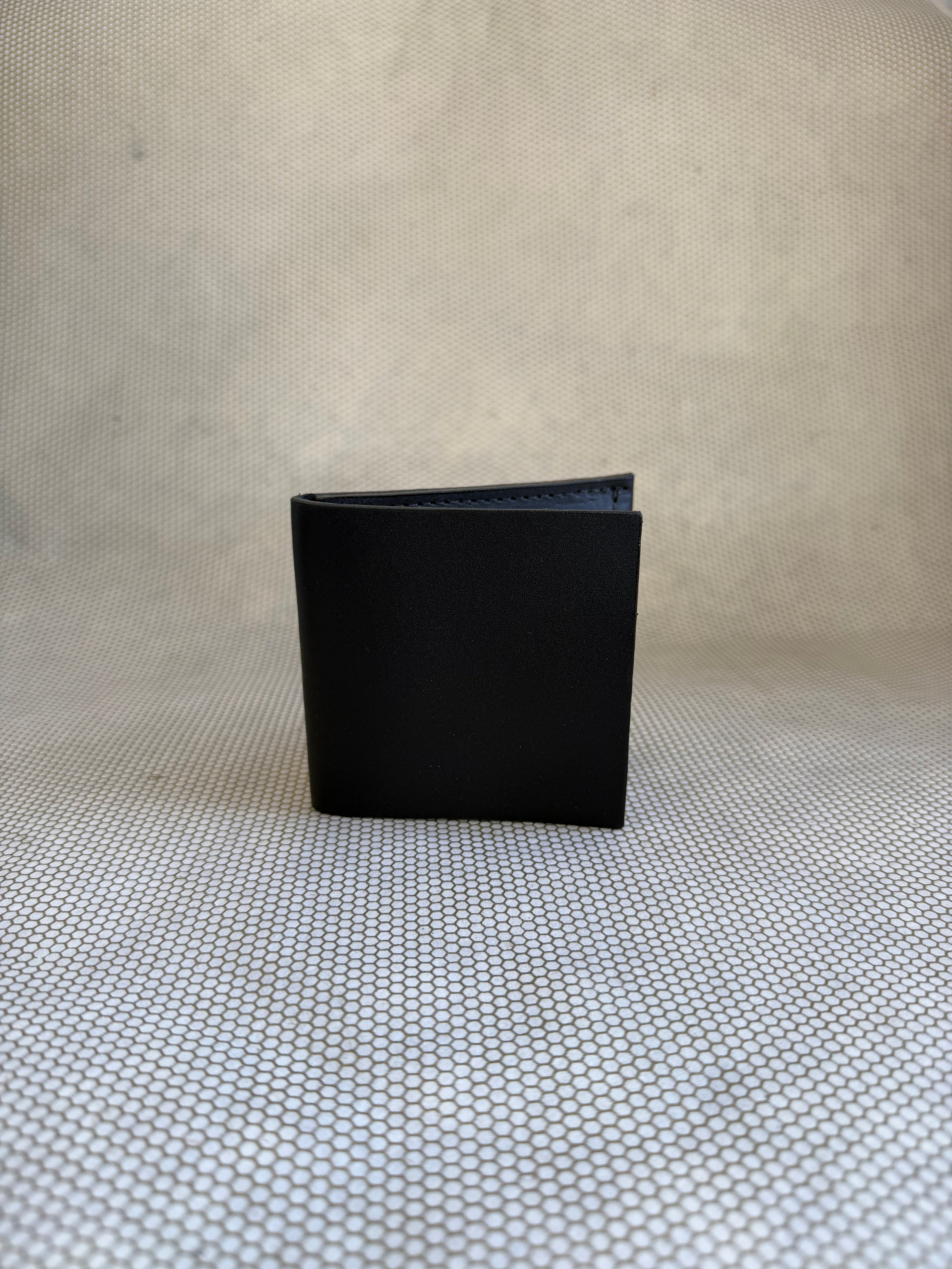 Black leather wallet on a textured beige surface