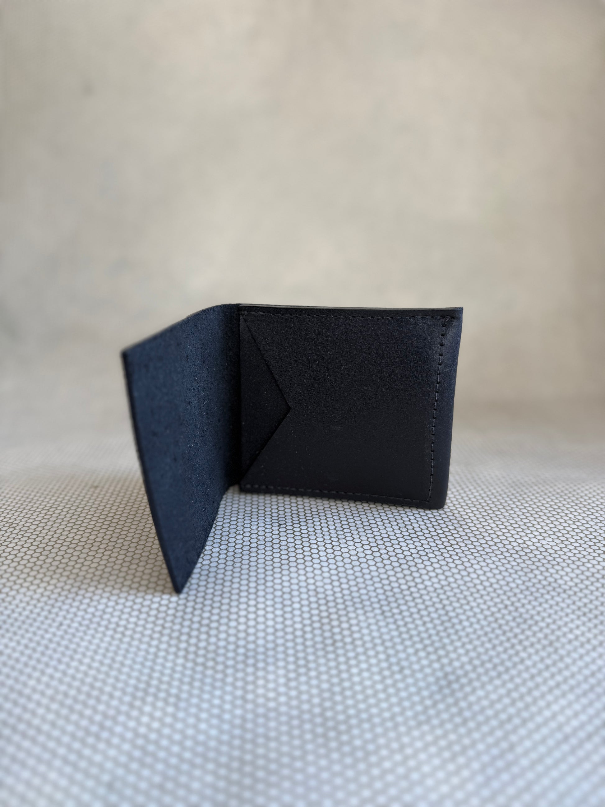 Black leather wallet on a textured beige surface