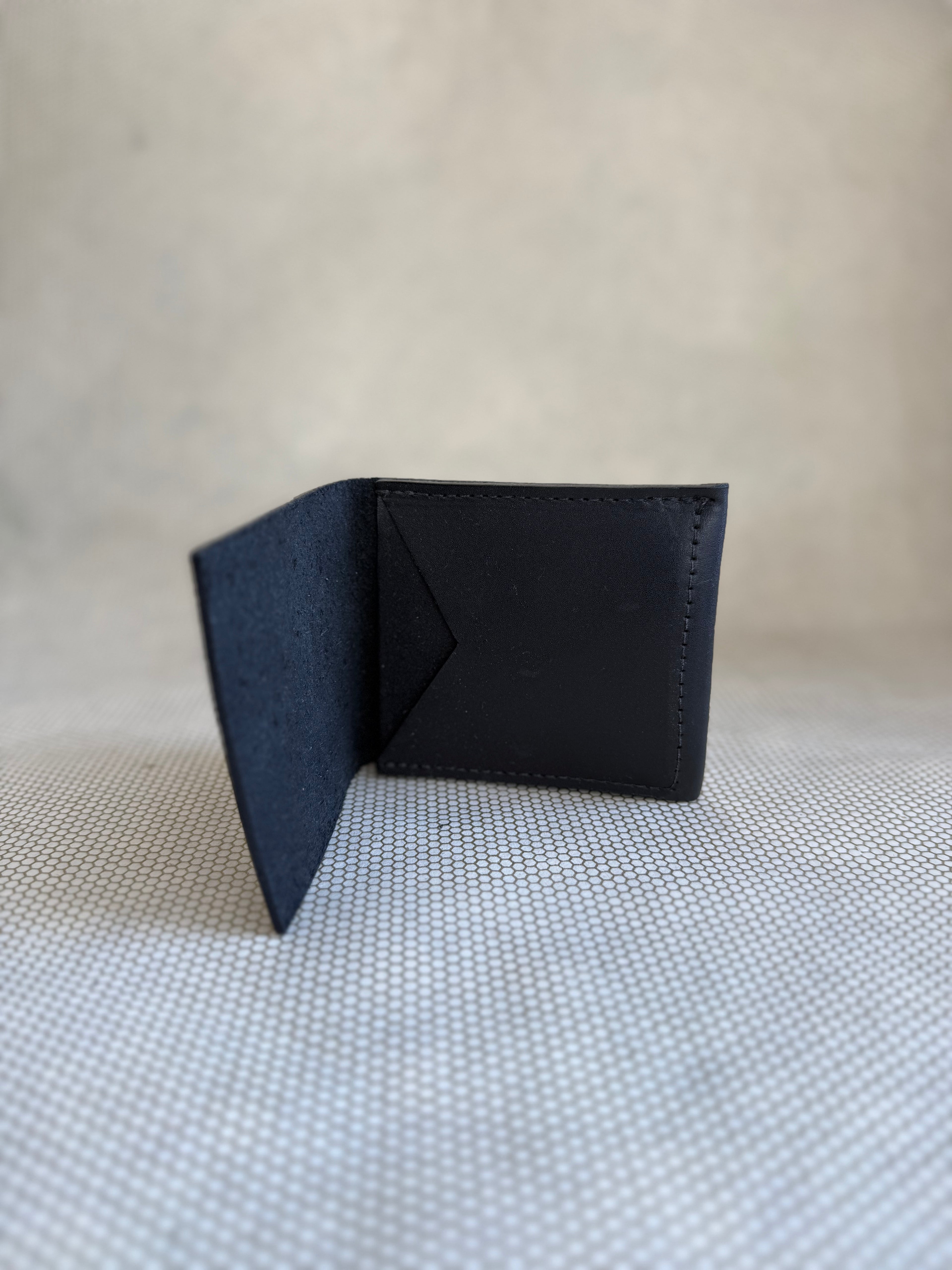 Black leather wallet on a textured beige surface