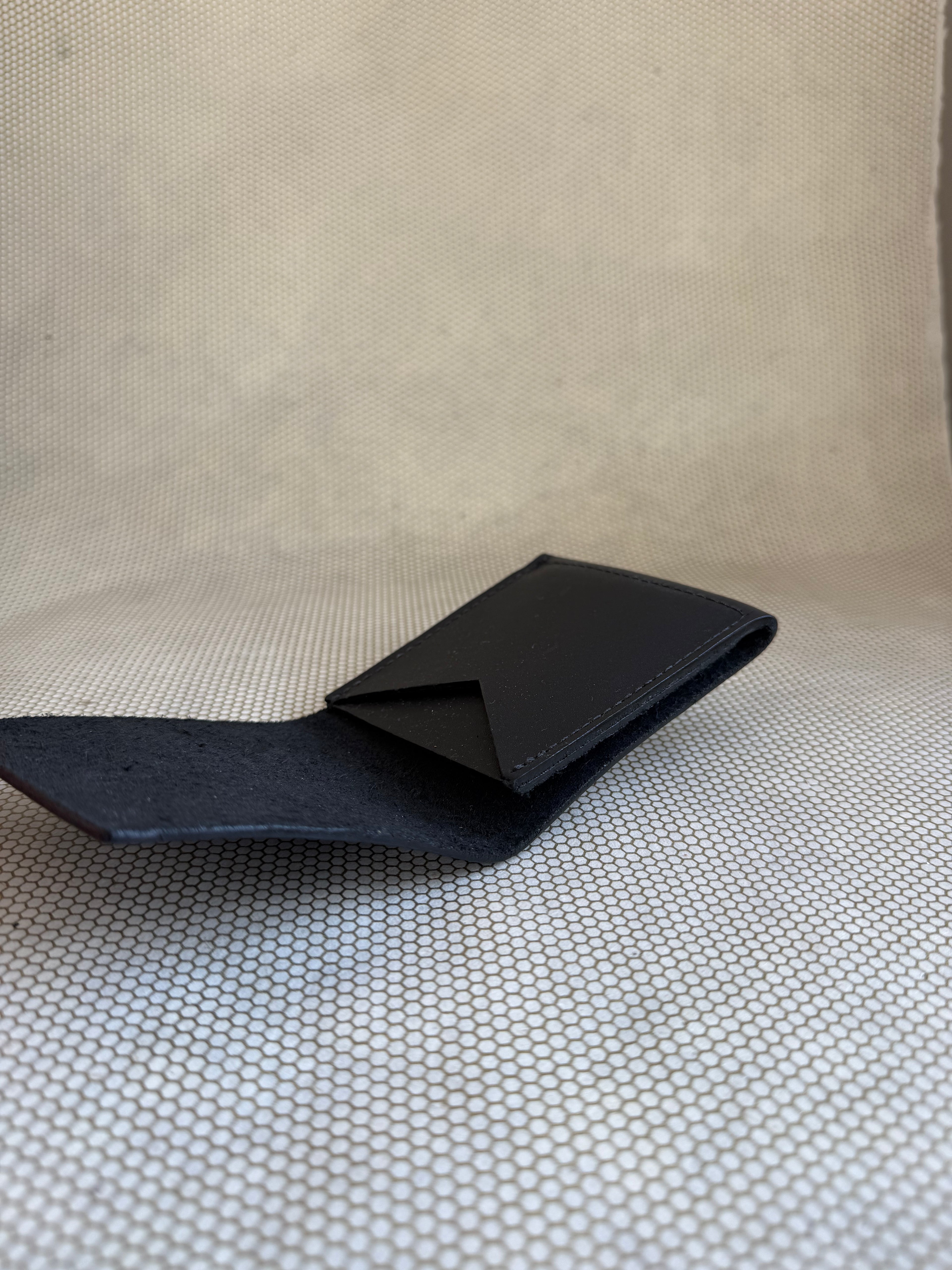 Black leather wallet on a textured beige surface