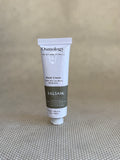 Osmology Balsam hand cream tube on a textured beige surface