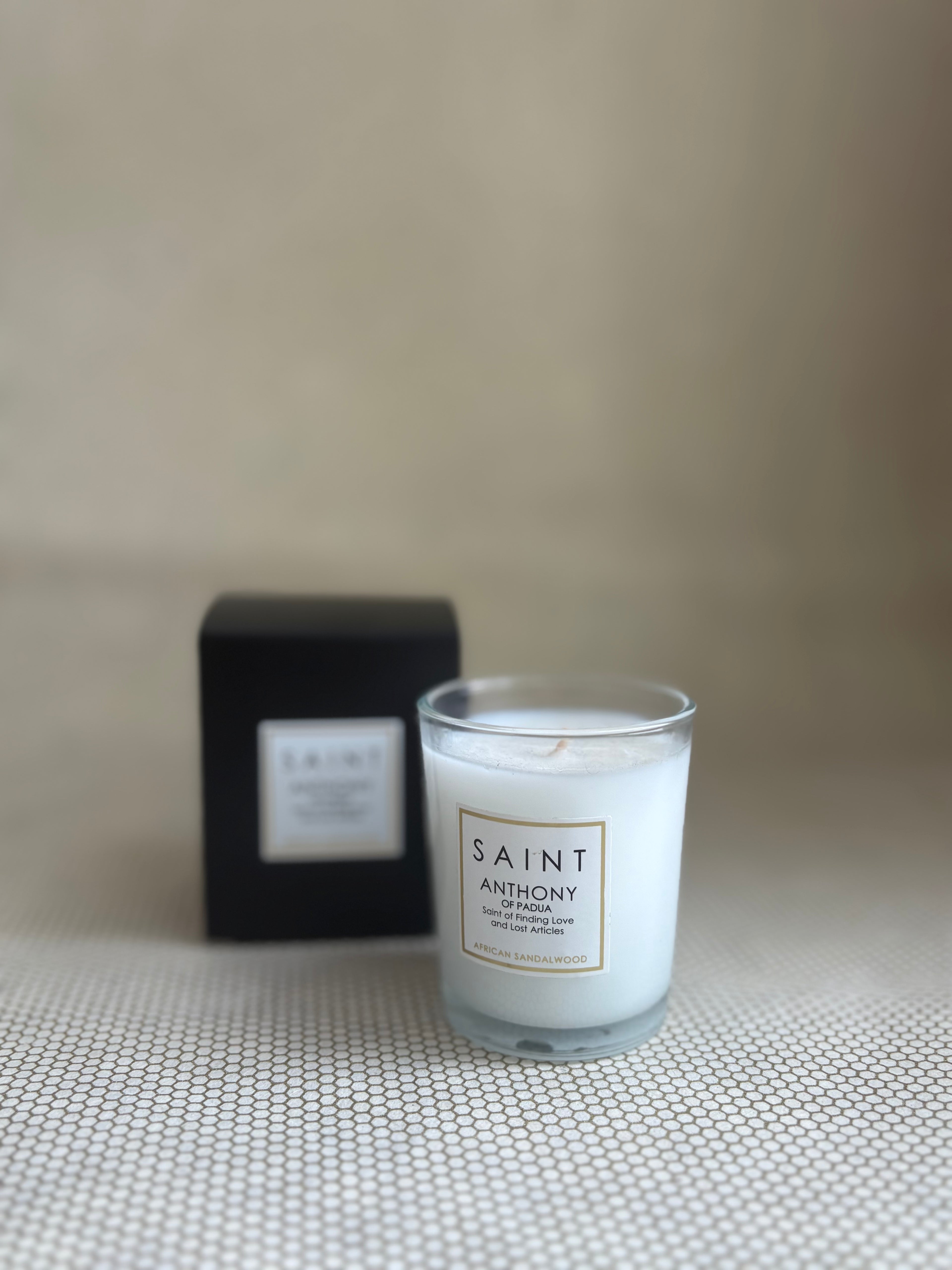 SAINT small votive candle. clear glass white wax in black box. saint anthony african sandalwood. 3 oz.(2.5 oz. pour). Measures 2.5"Hx2"D.