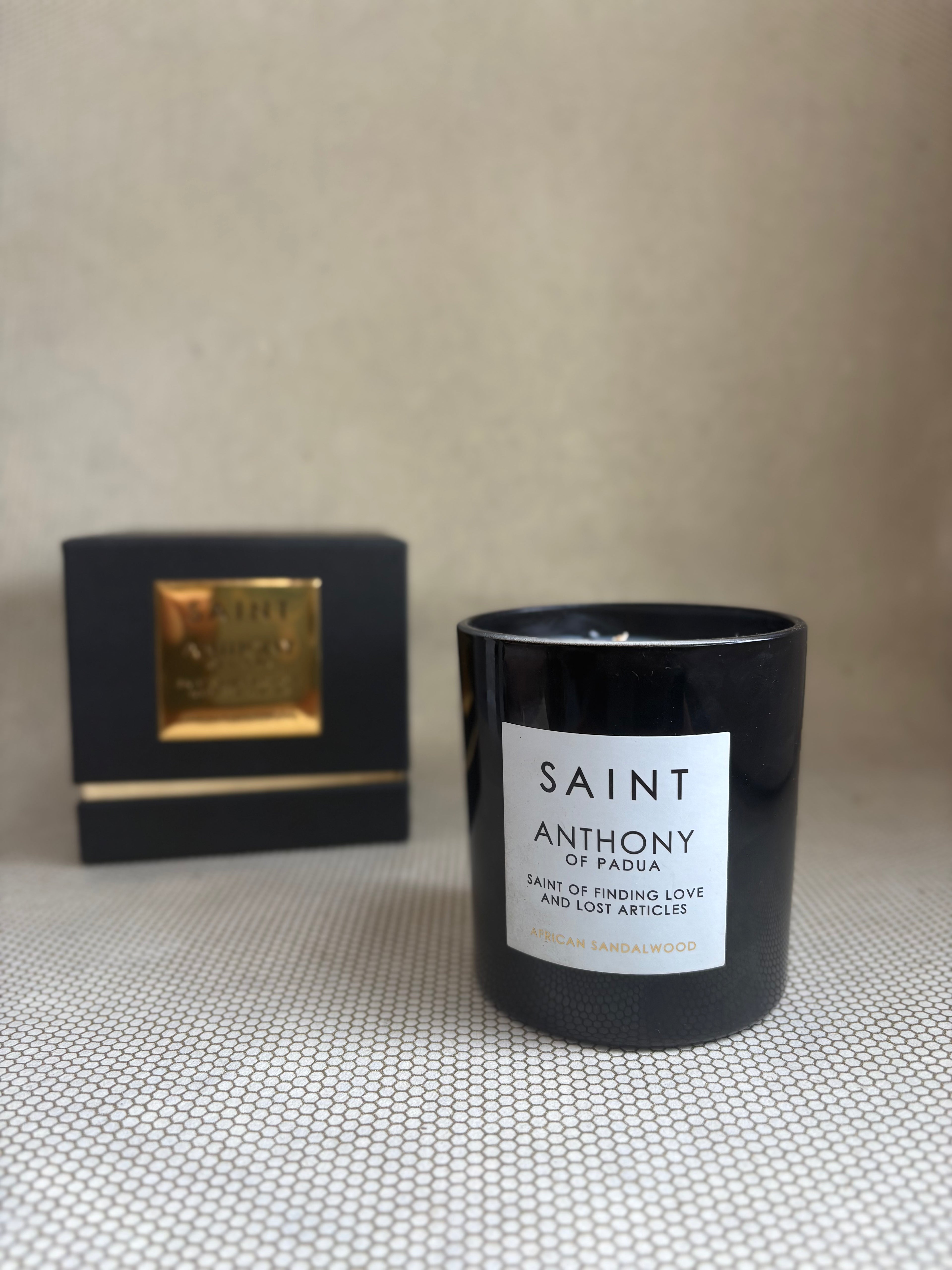 SAINT black glass candle with gold lid. black and gold box for candle. saint anthony african sandalwood. 11 oz. (8 oz. pour), Measures 3.5" H x 3" D. 