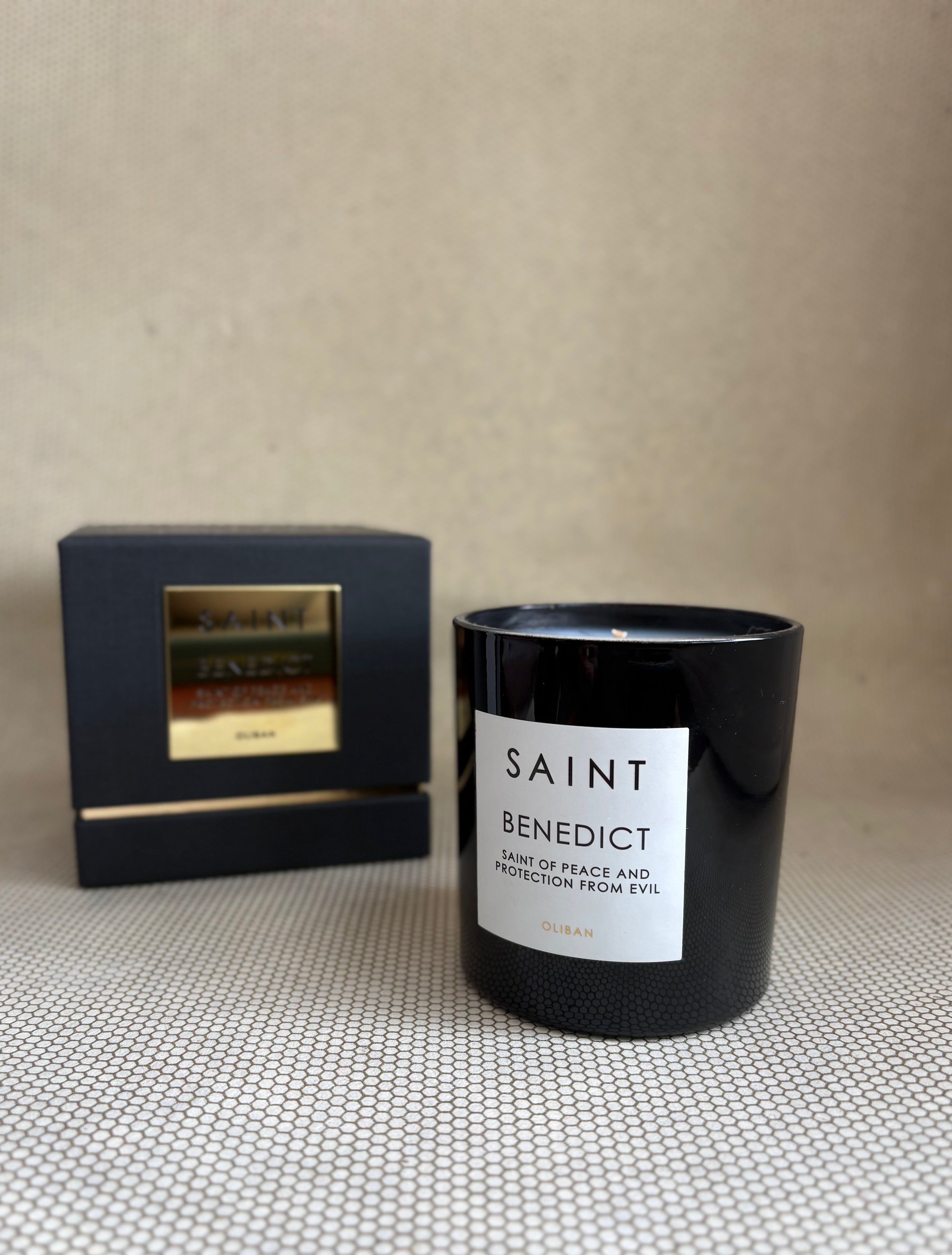 SAINT black glass candle with gold lid. black and gold box for candle. saint benedict oliban. 11 oz. (8 oz. pour), Measures 3.5" H x 3" D. 