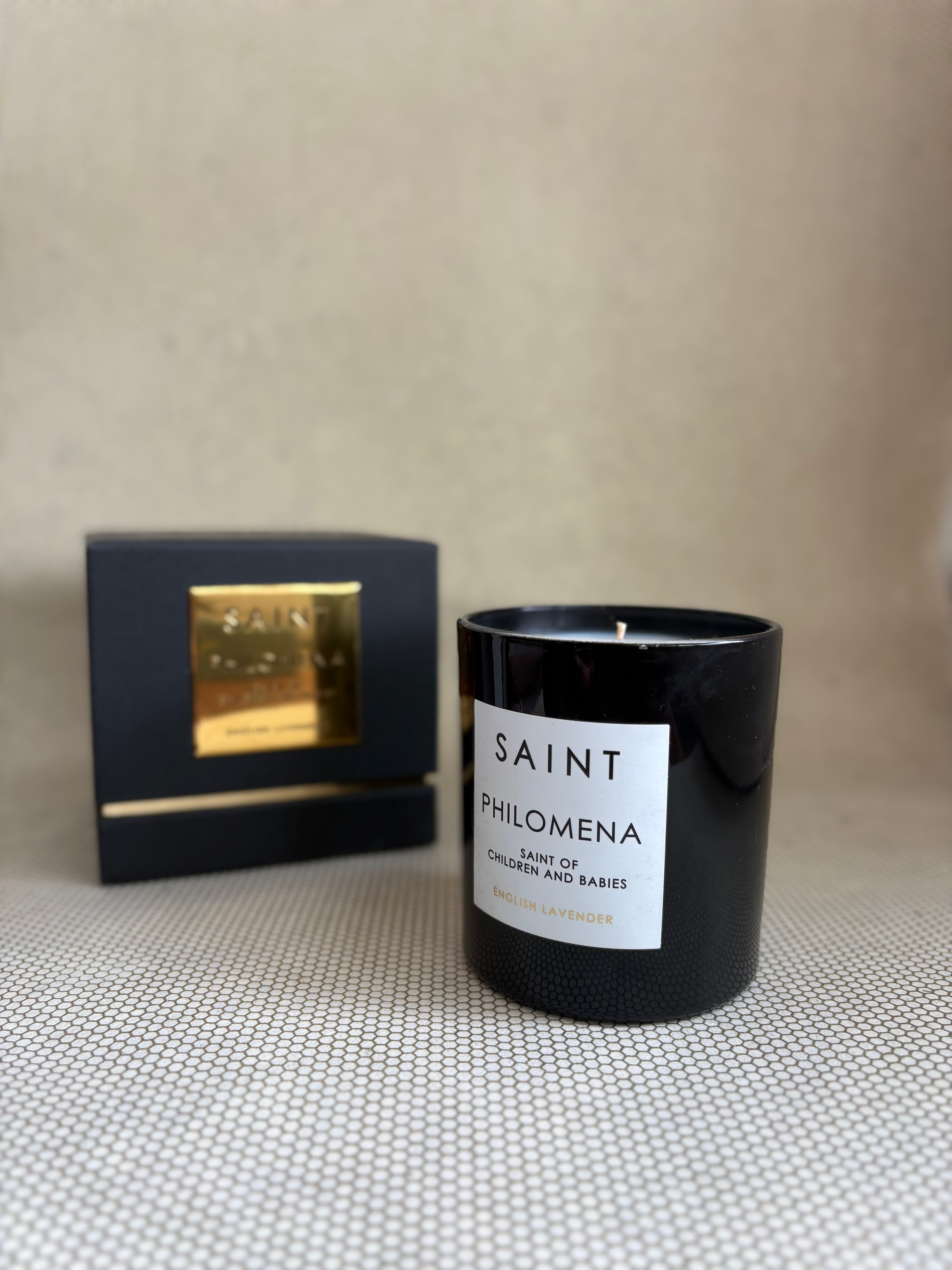SAINT black glass candle with gold lid. black and gold box for candle. saint philomena english lavender. 11 oz. (8 oz. pour), Measures 3.5" H x 3" D.