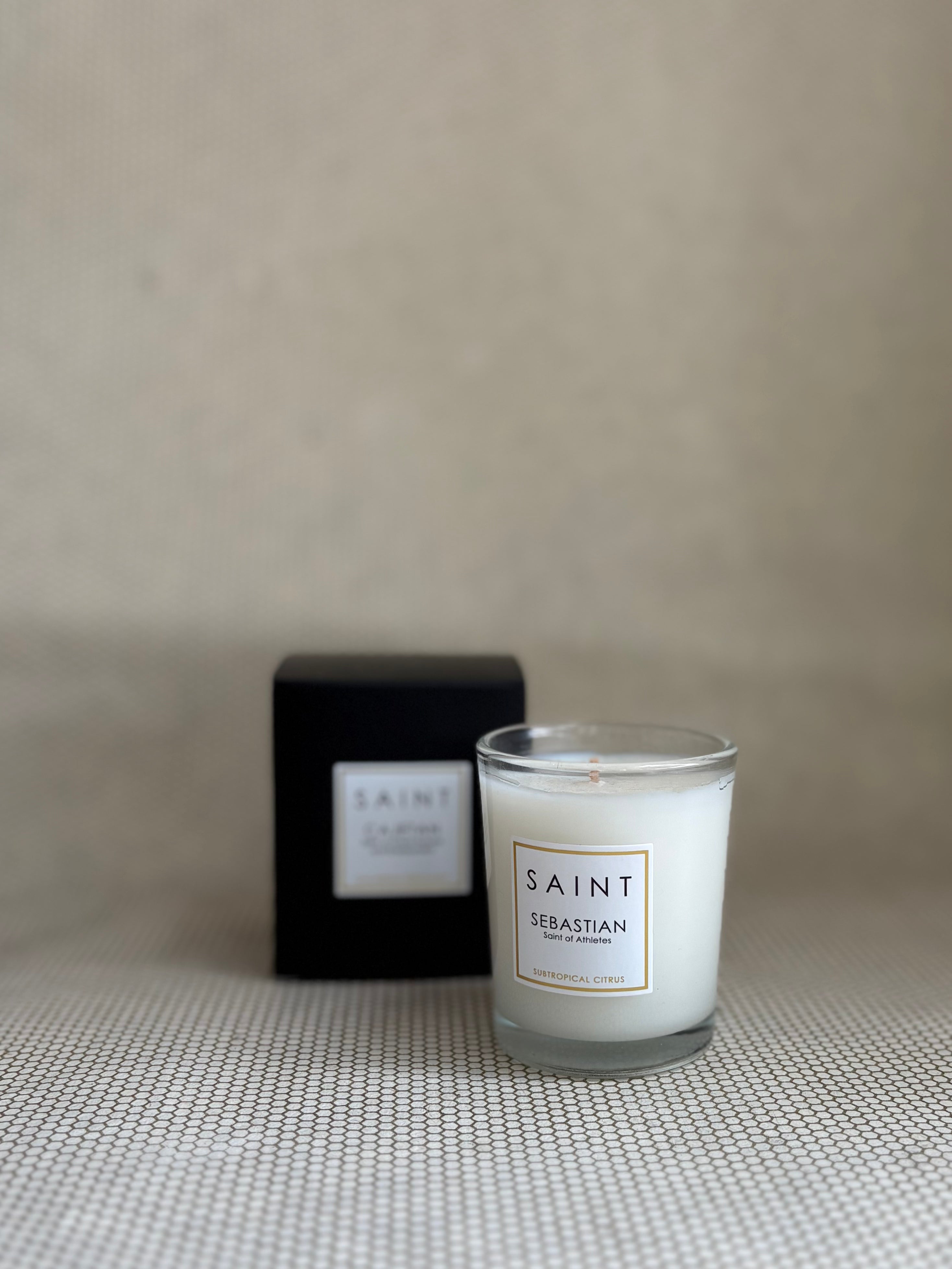 SAINT small votive candle. clear glass white wax in black box. saint sebastian citrus. 3 oz.(2.5 oz. pour). Measures 2.5"Hx2"D.