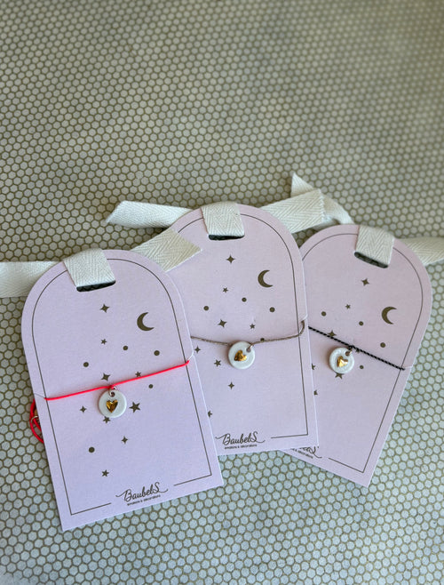 pink cardboard packaging and string charm bracelets with heart. 