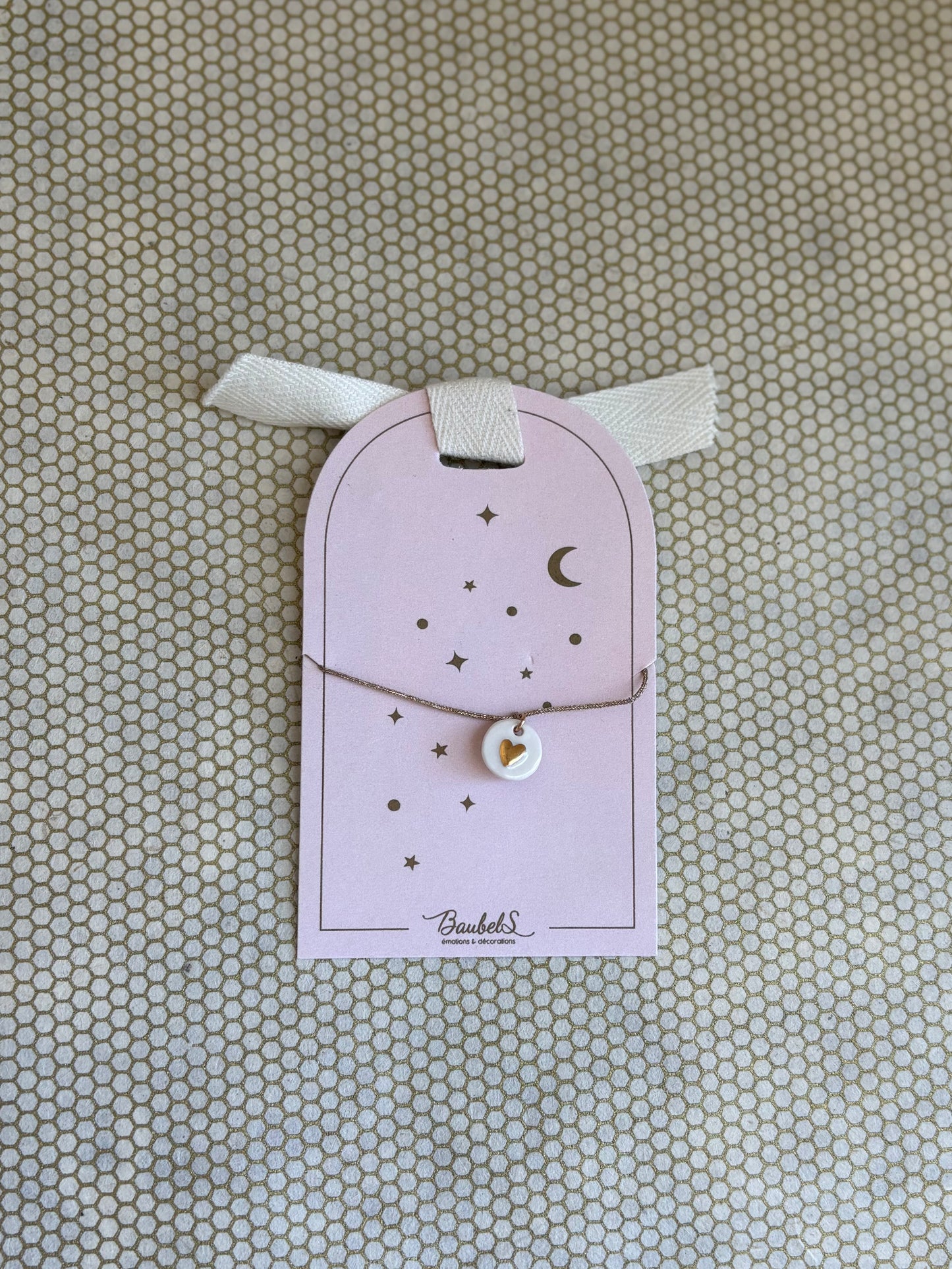pink cardboard packaging and gold string charm bracelet with heart. 