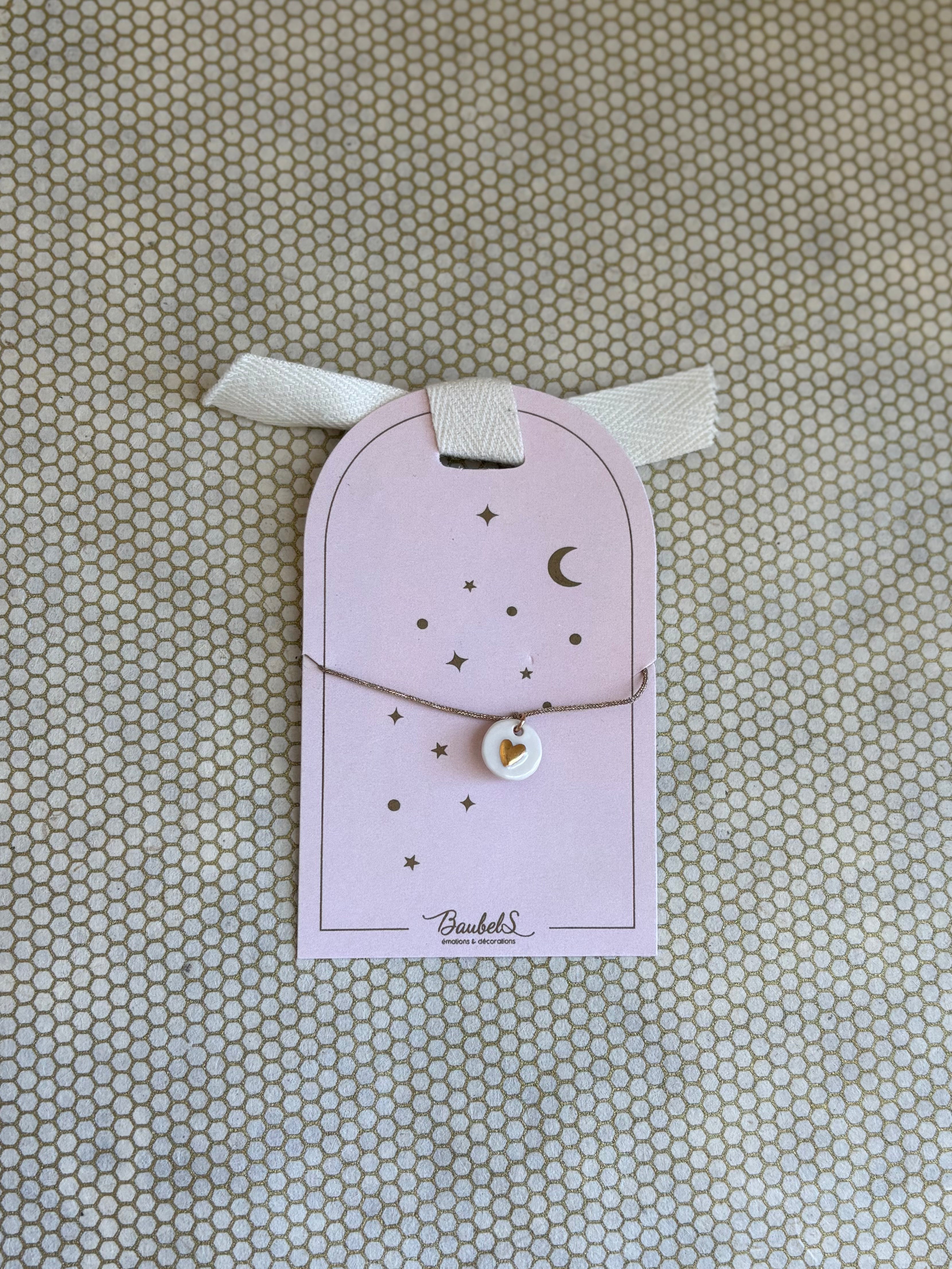 pink cardboard packaging and gold string charm bracelet with heart. 