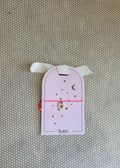 pink cardboard packaging and pink string charm bracelet with heart. 