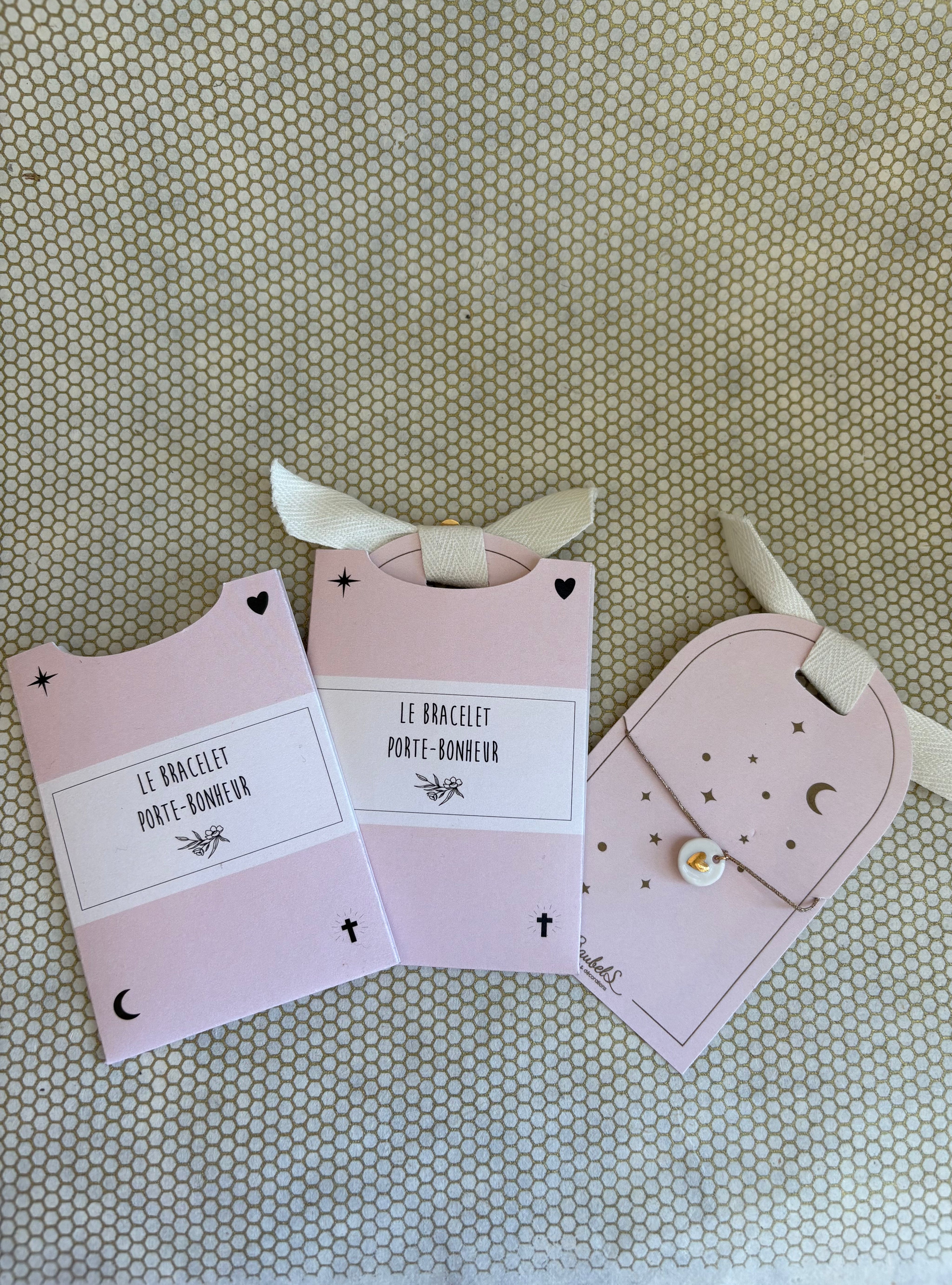 pink cardboard packaging and string charm bracelet with heart. 
