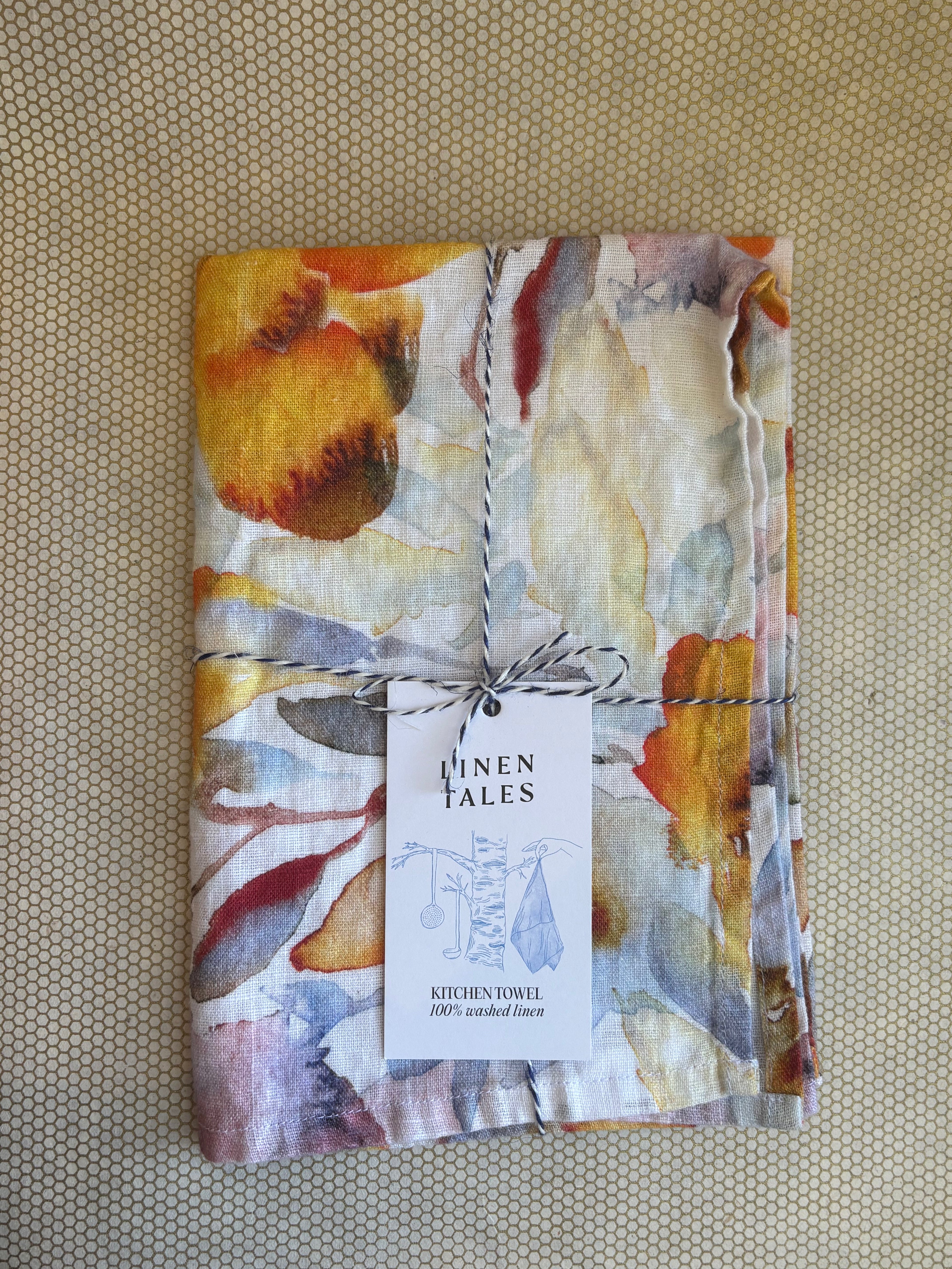 stacked kitchen towels. orange, red, blue, yellow, purple citrus print on white linen background. Linen Tales 100% linen 18''x26''