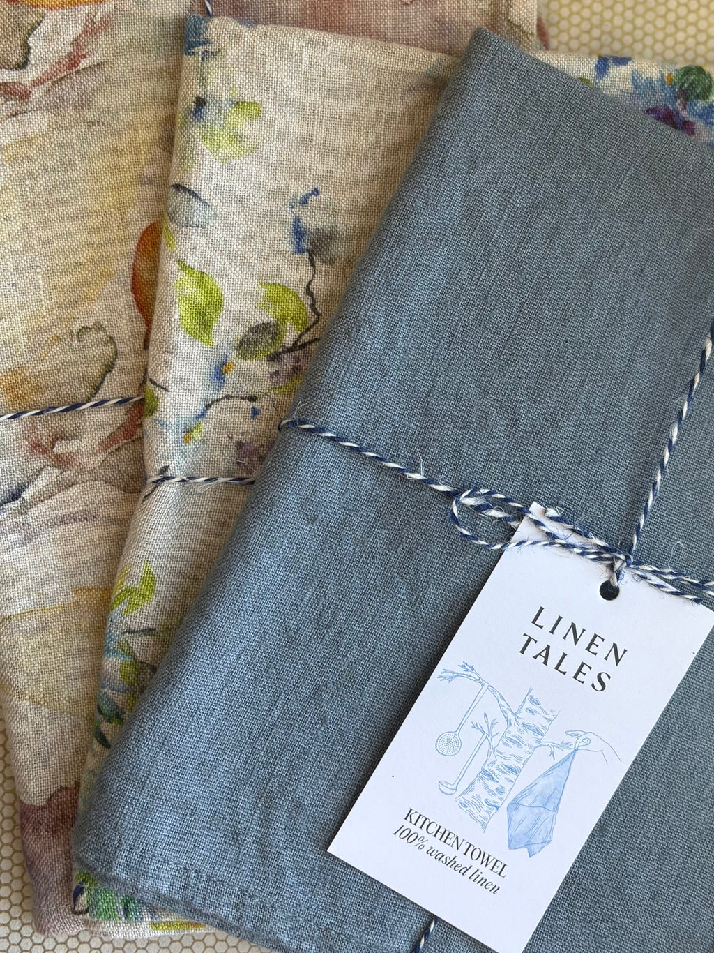 stacked kitchen towels in varying colors. Linen Tales 100% linen 18''x26''