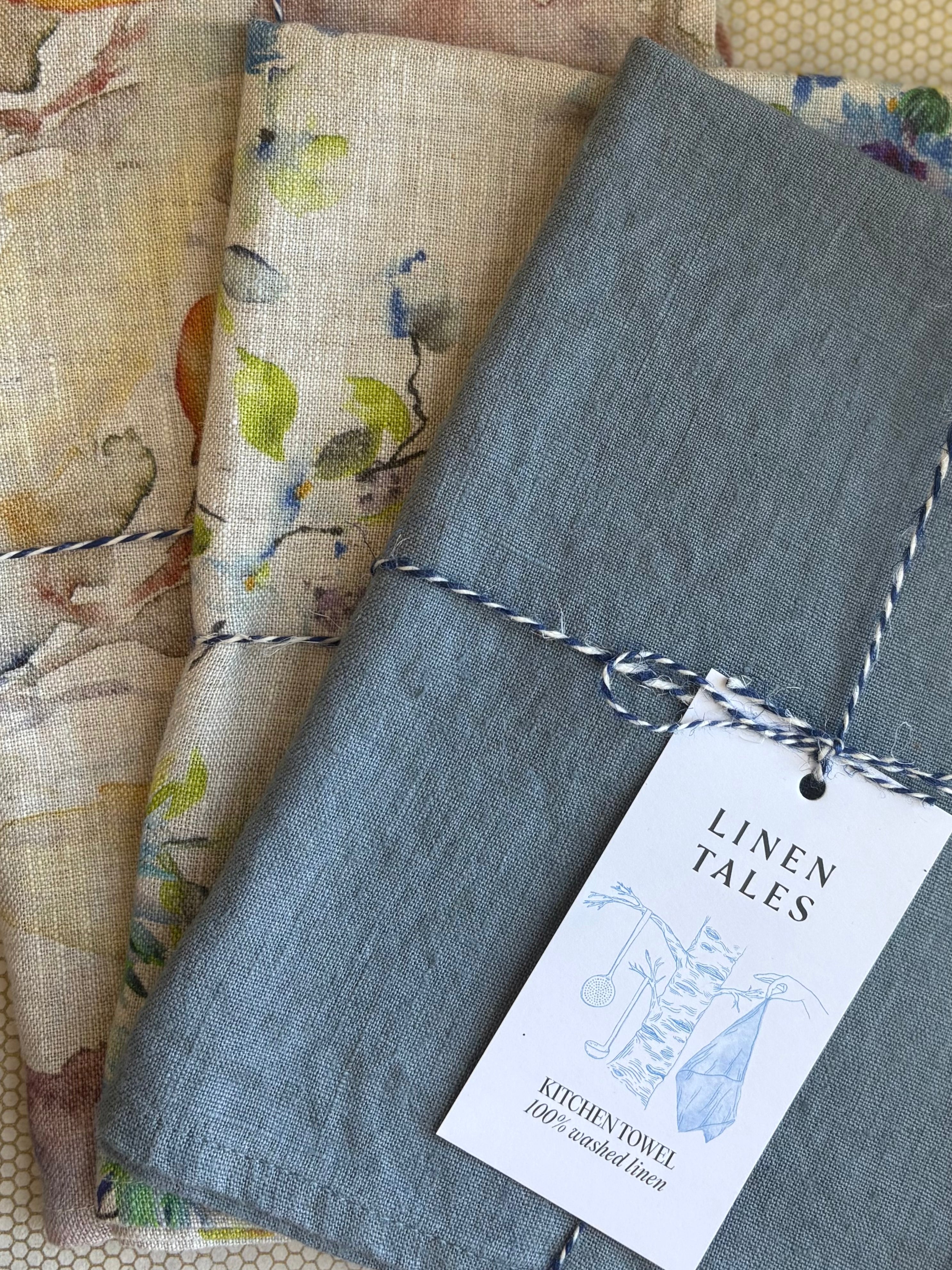 stacked kitchen towels in varying colors. Linen Tales 100% linen 18''x26''