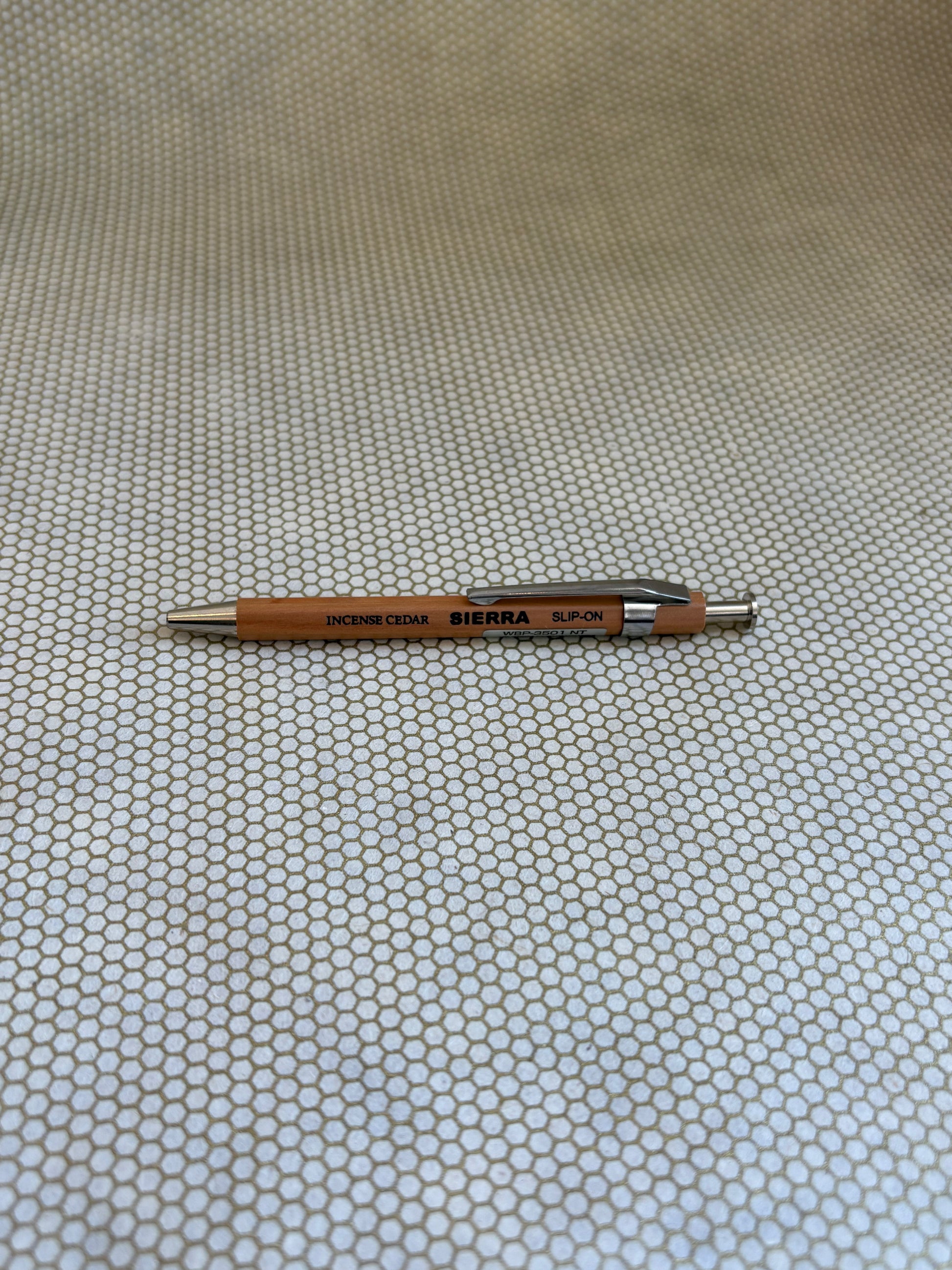 wooden ballpoint pen with Sierra branding on a textured beige background