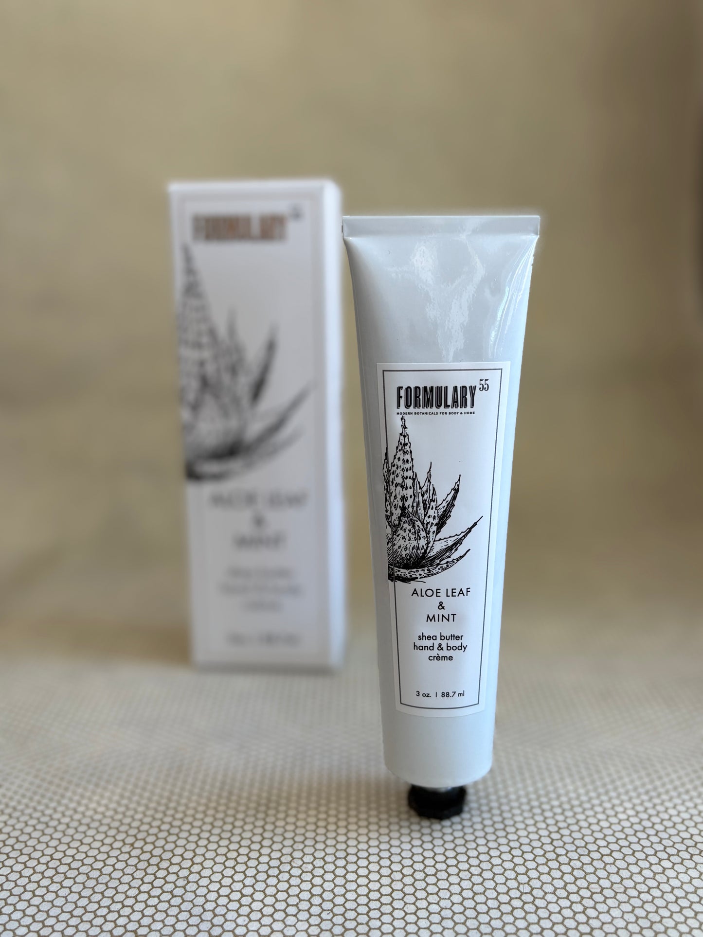 Tube of Formulary 55 aloe vera hand and body lotion on a neutral background with white box in background. 