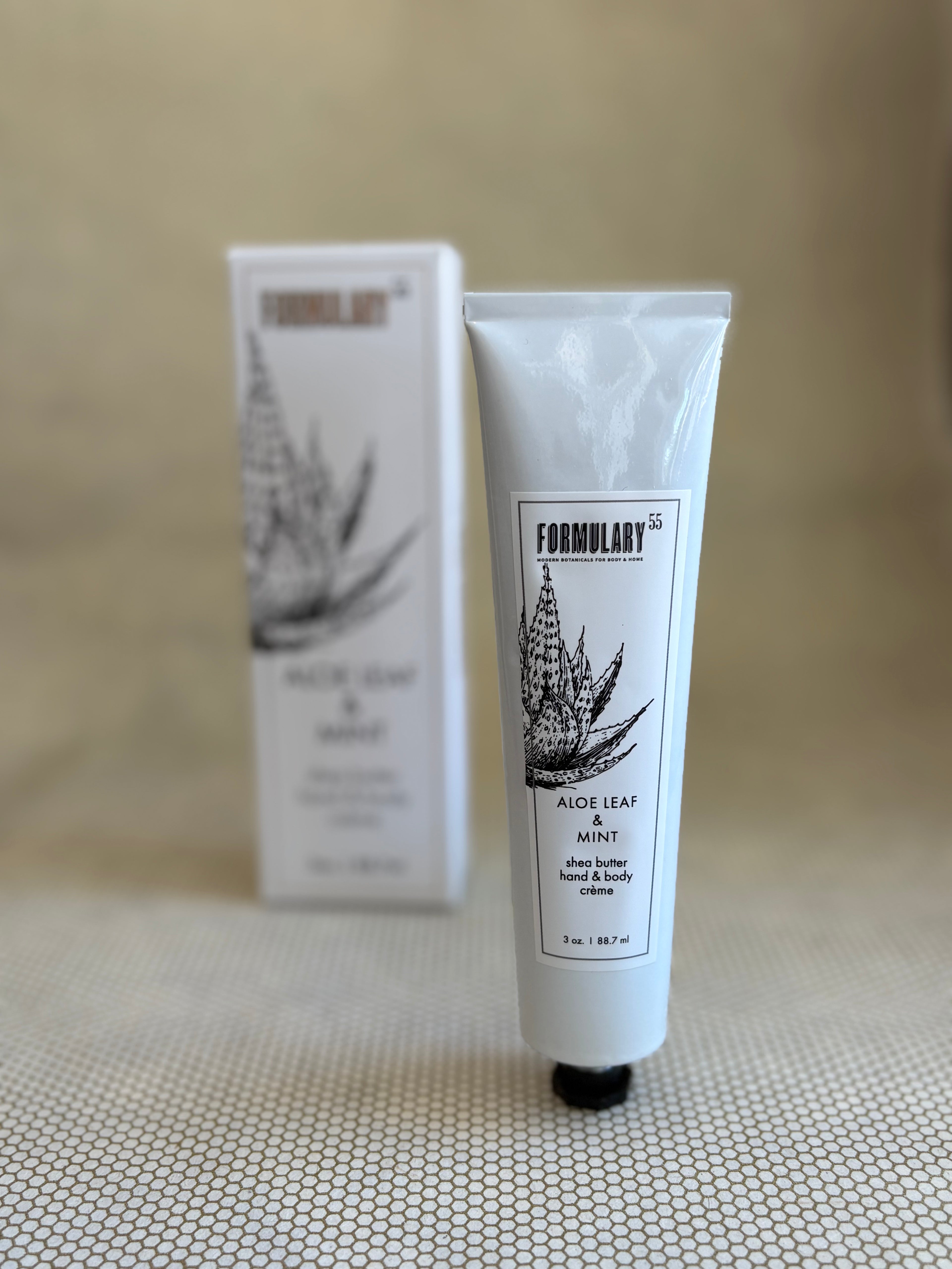 Tube of Formulary 55 aloe vera hand and body lotion on a neutral background with white box in background. 