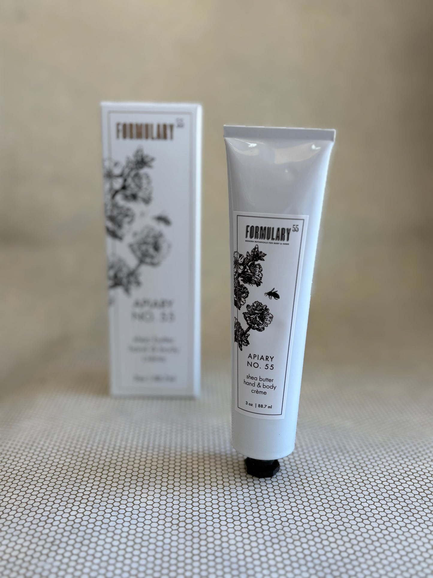 White tube of Formulary 55 apiary hand and body lotion with white packaging box in background. 