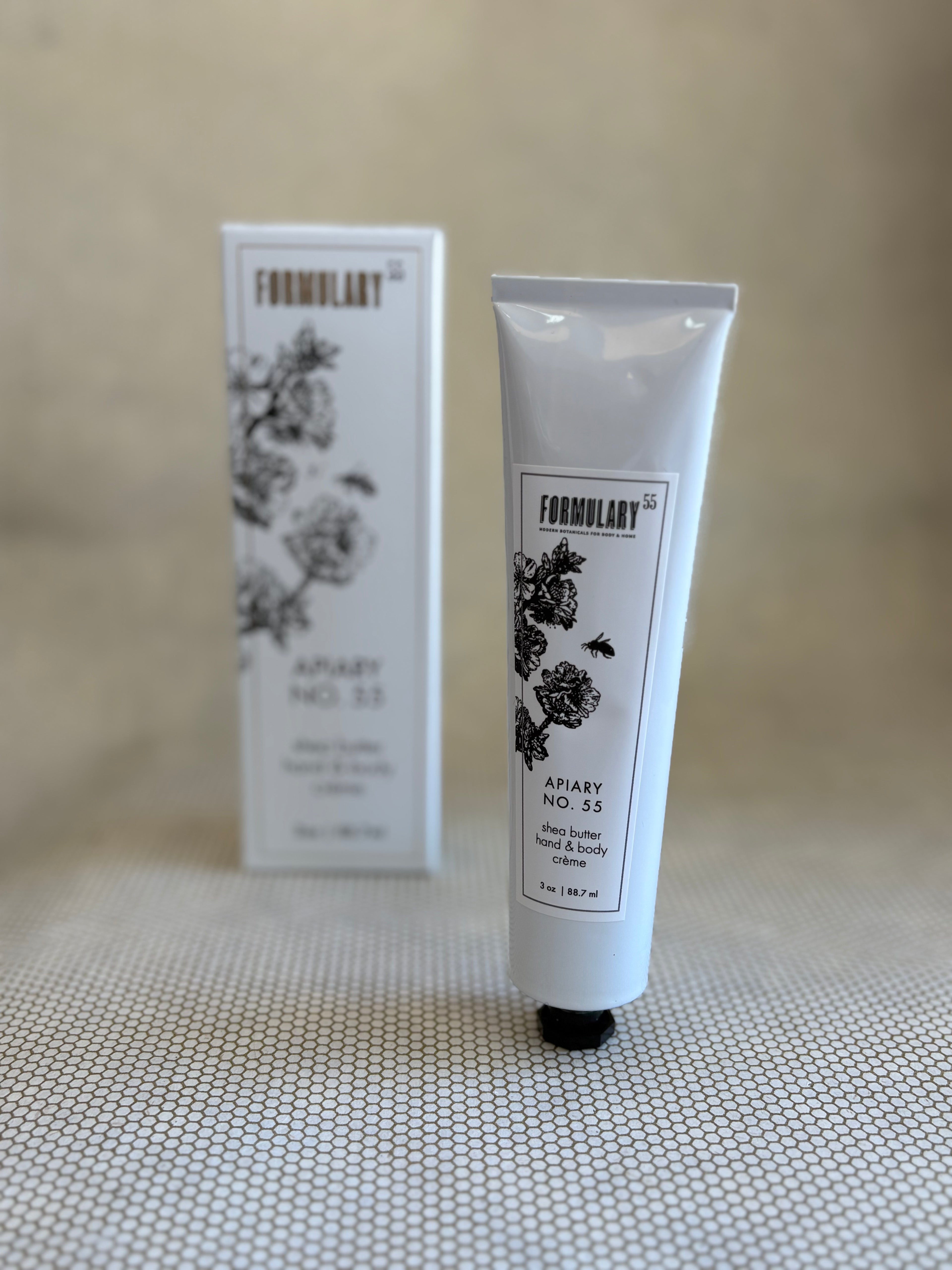 White tube of Formulary 55 apiary hand and body lotion with white packaging box in background. 