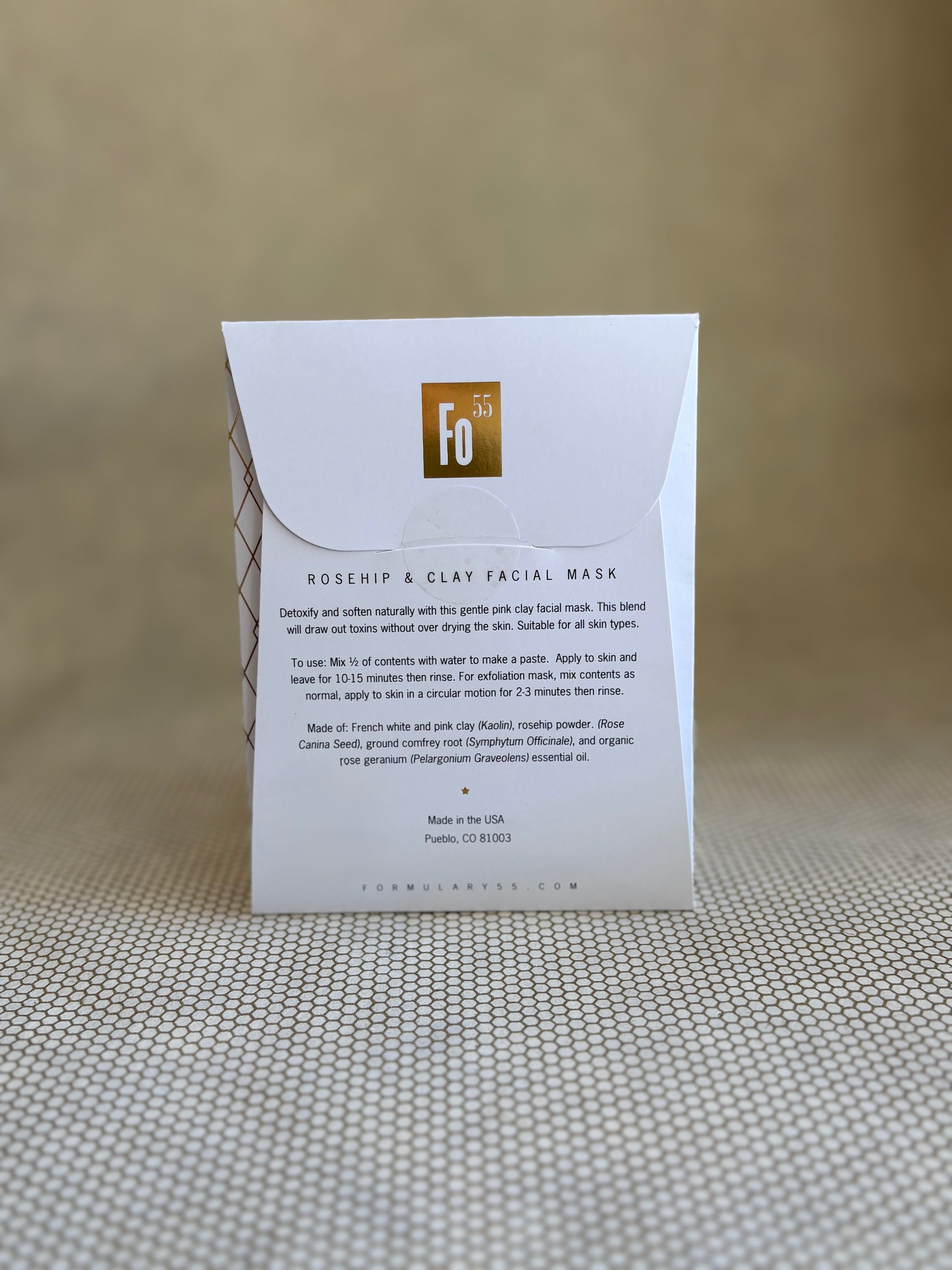 back of Formulary 55 rosehip and clay facial mask packaging on a textured surface with a neutral background