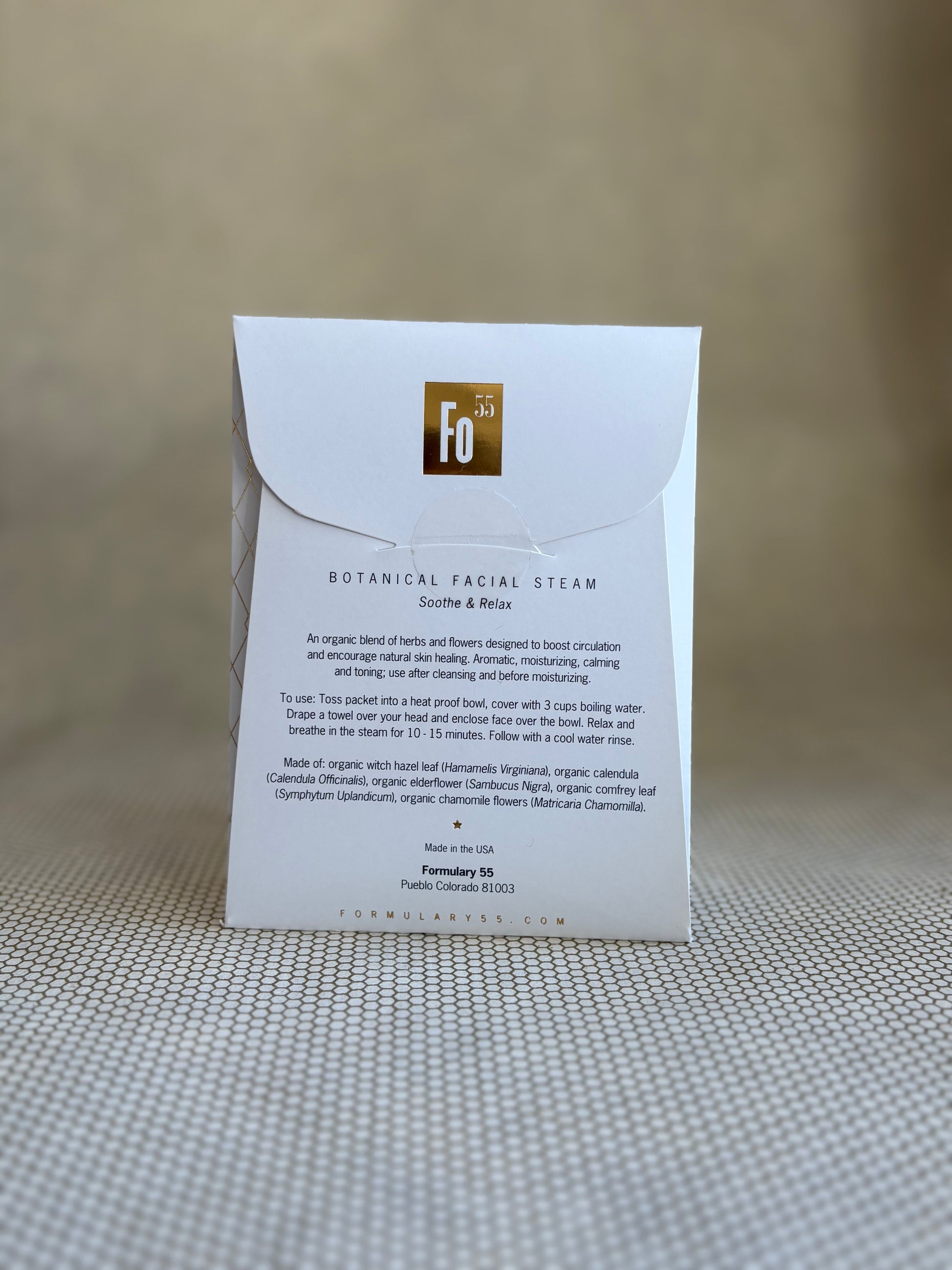 back of Formulary 55 botanical facial steam packaging on a textured surface with a neutral background
