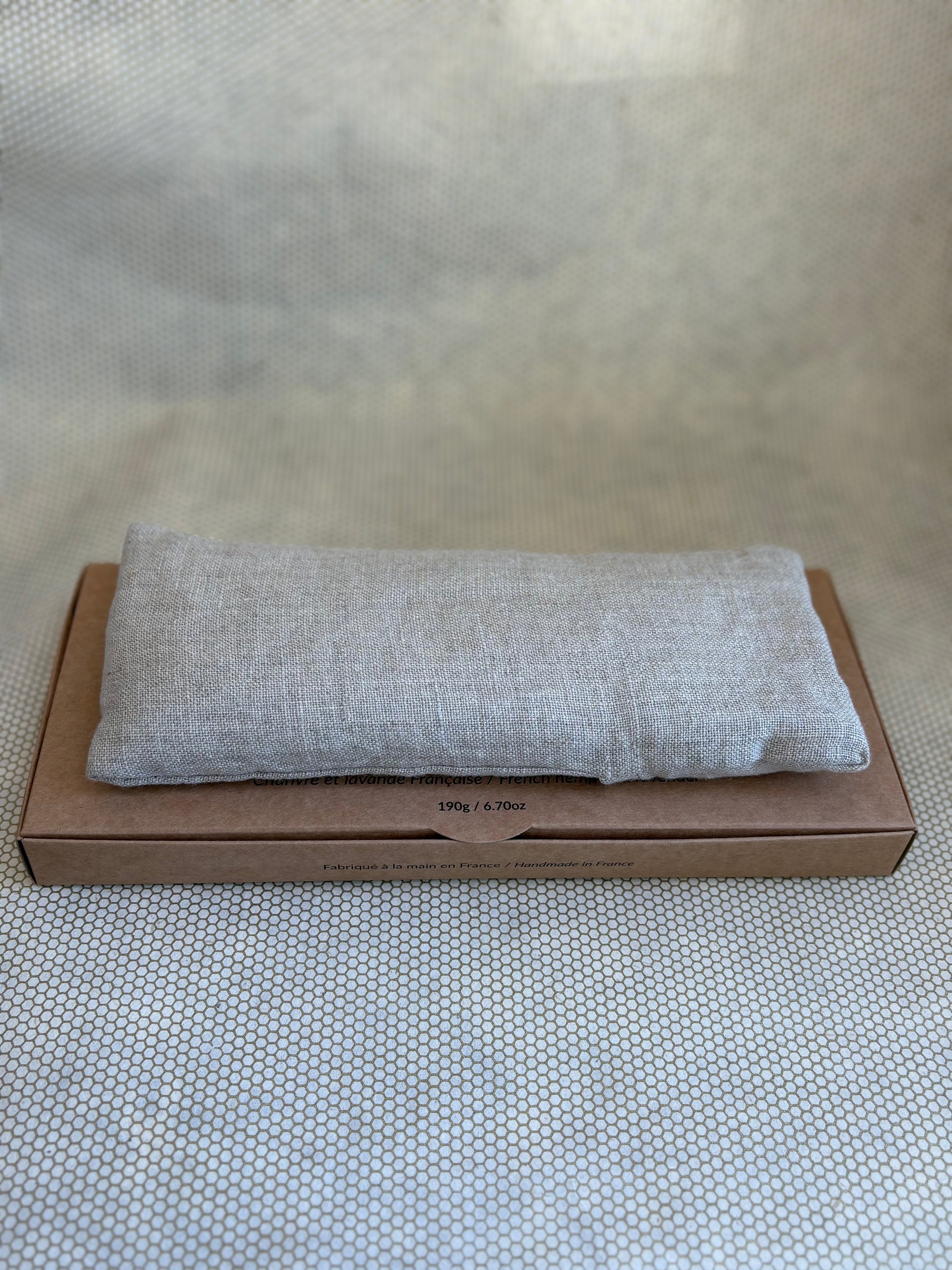 Gray eye pillow on a cardboard box on a textured surface