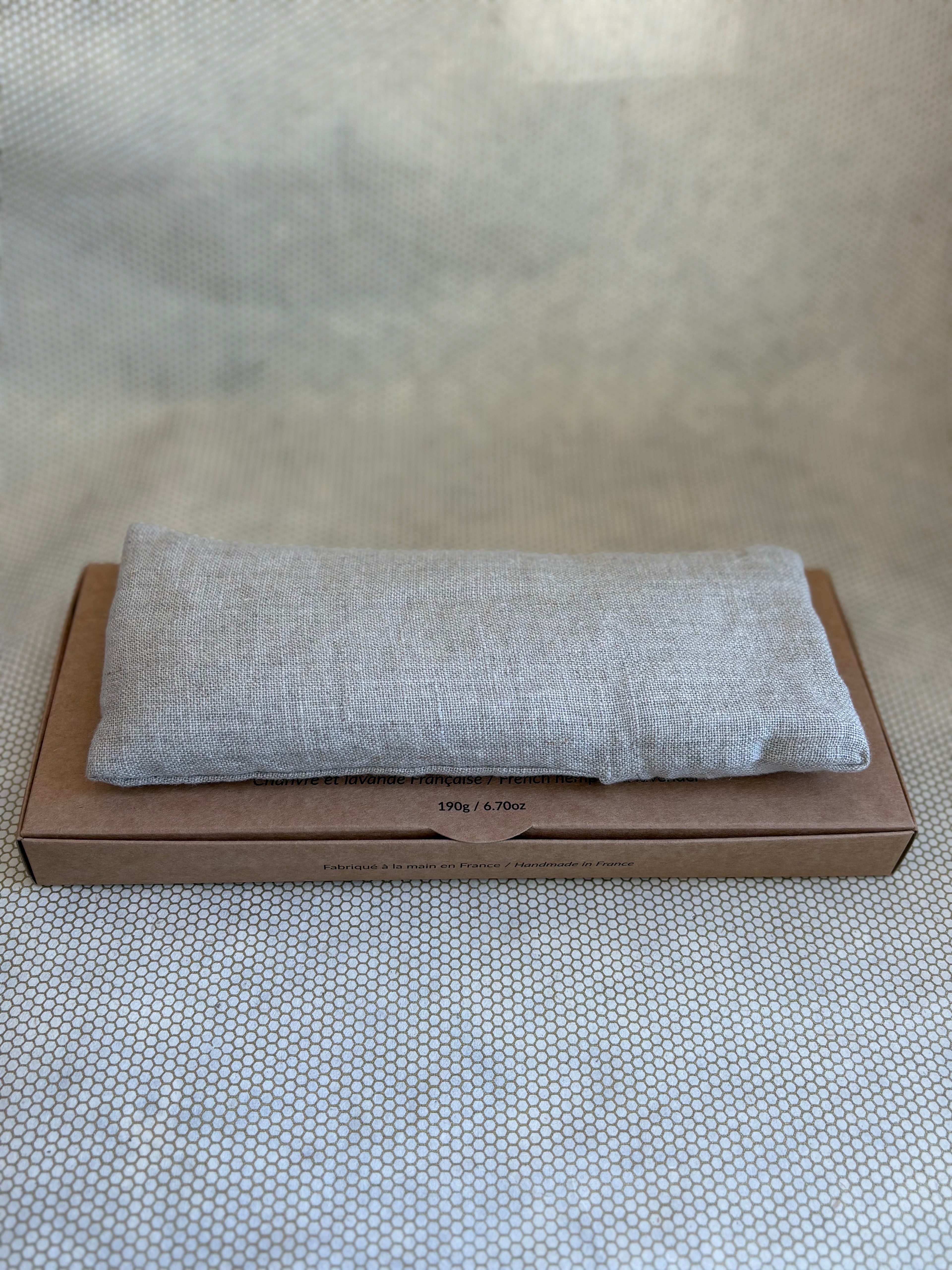 Gray eye pillow on a cardboard box on a textured surface