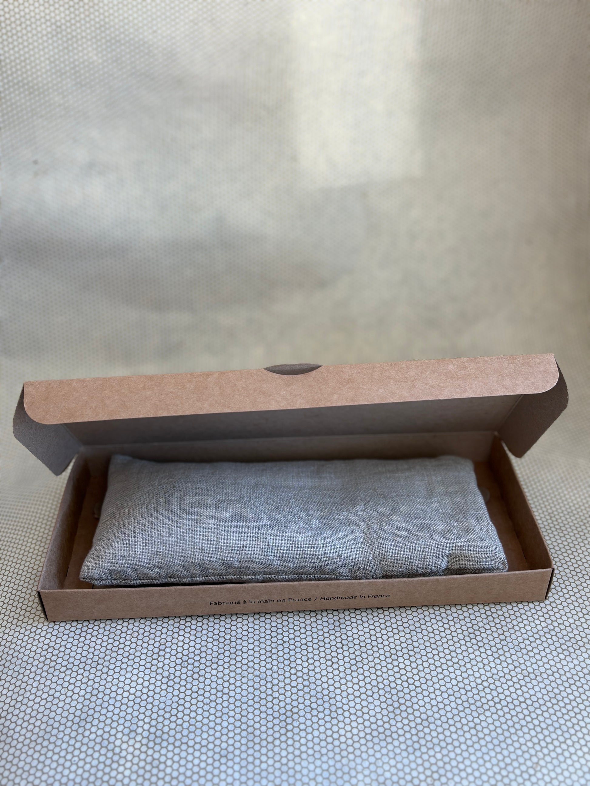 grey eye pillow in a brown cardboard box 