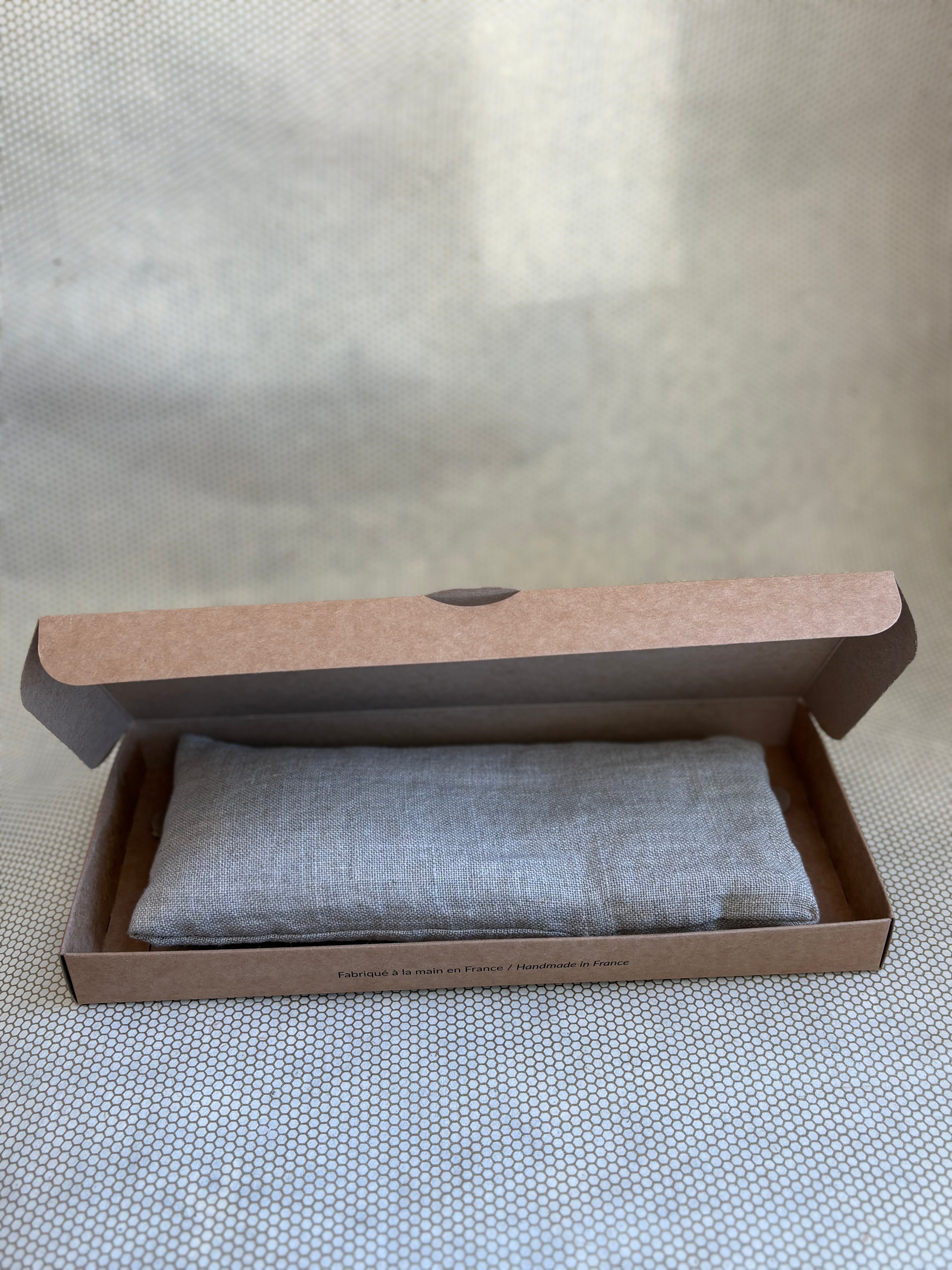 grey eye pillow in a brown cardboard box 