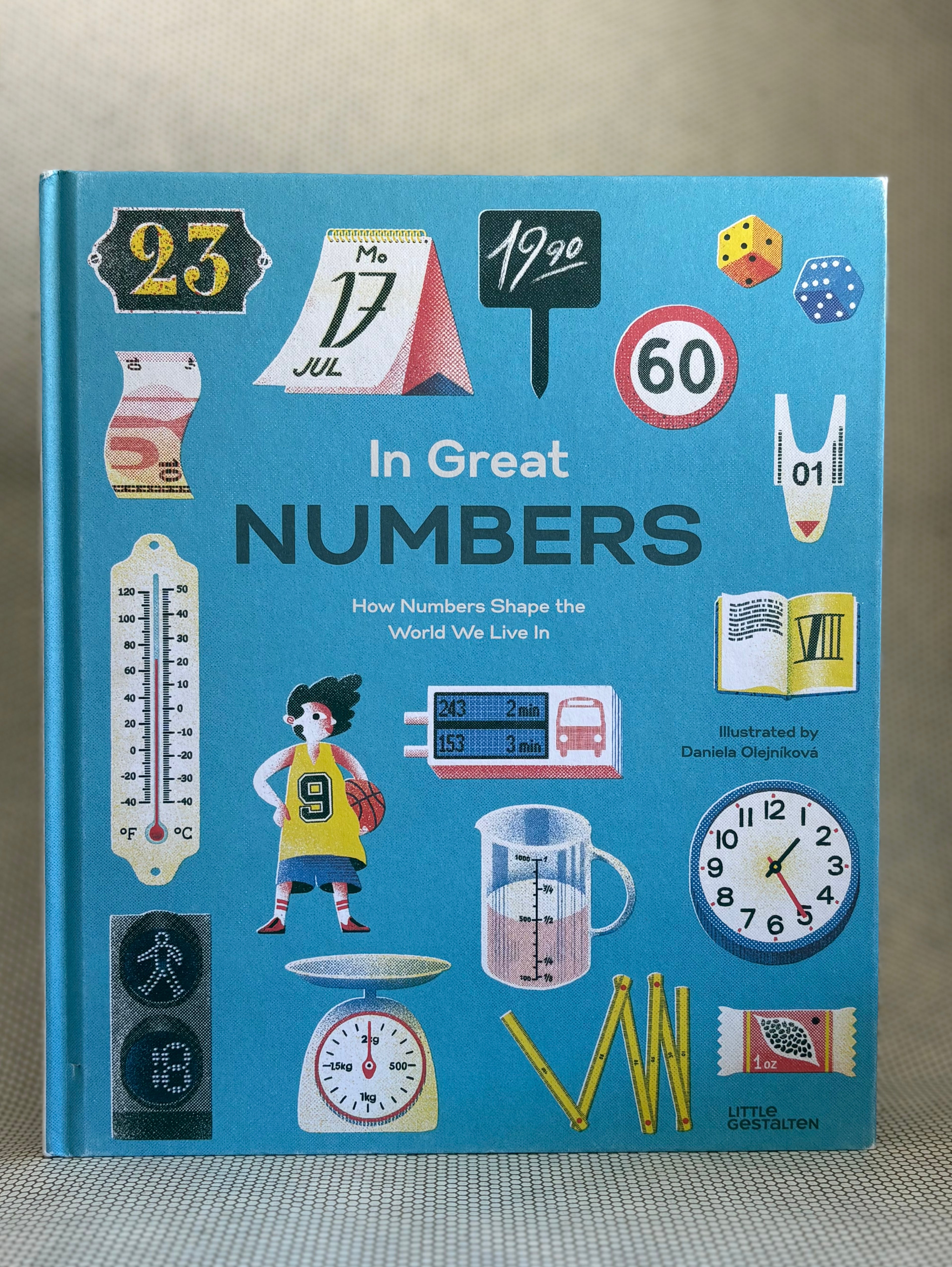 Book titled 'In Great Numbers' with various illustrations on a blue background