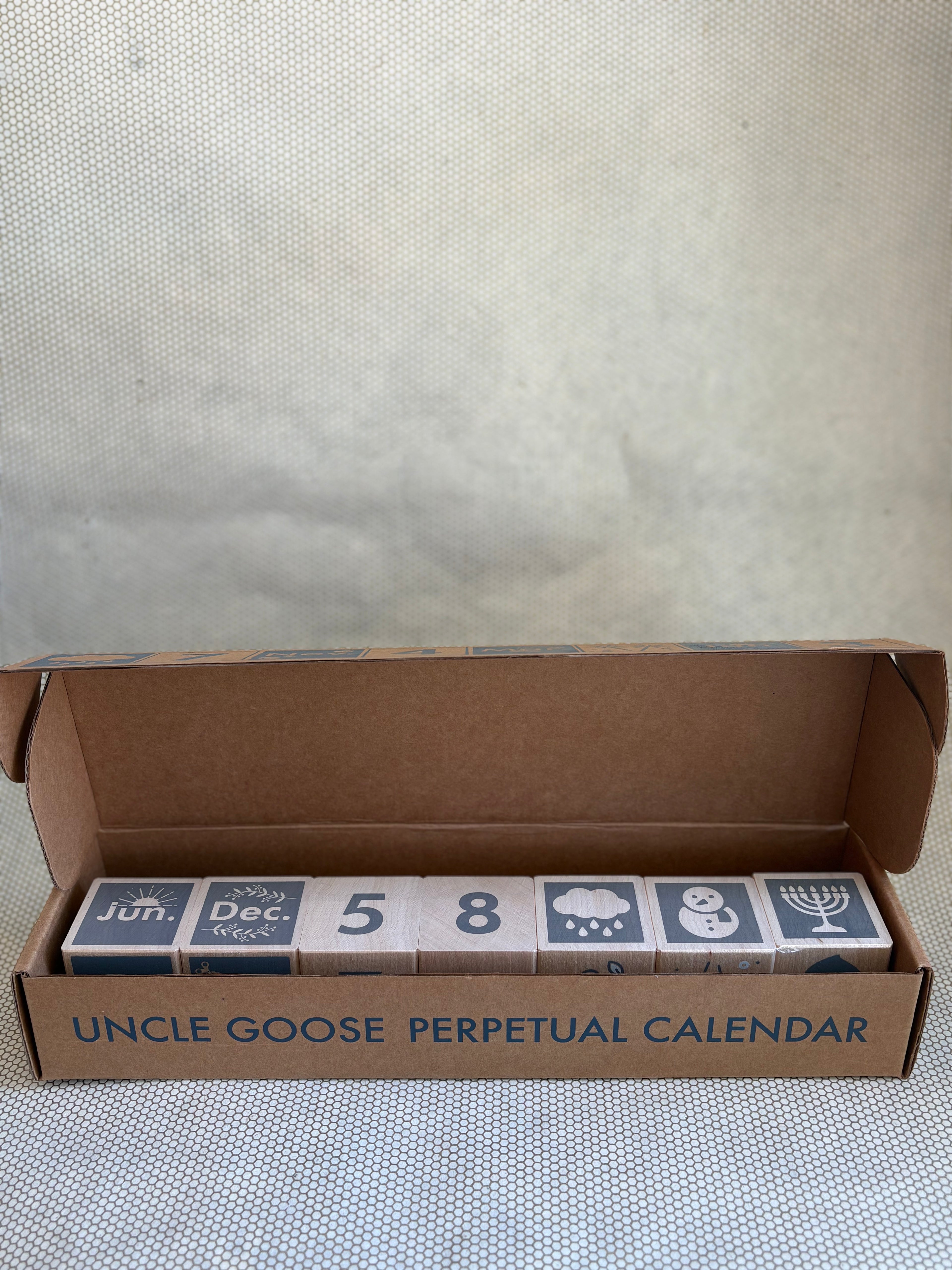 Uncle Goose Perpetual Calendar blocks in packaging on a textured surface